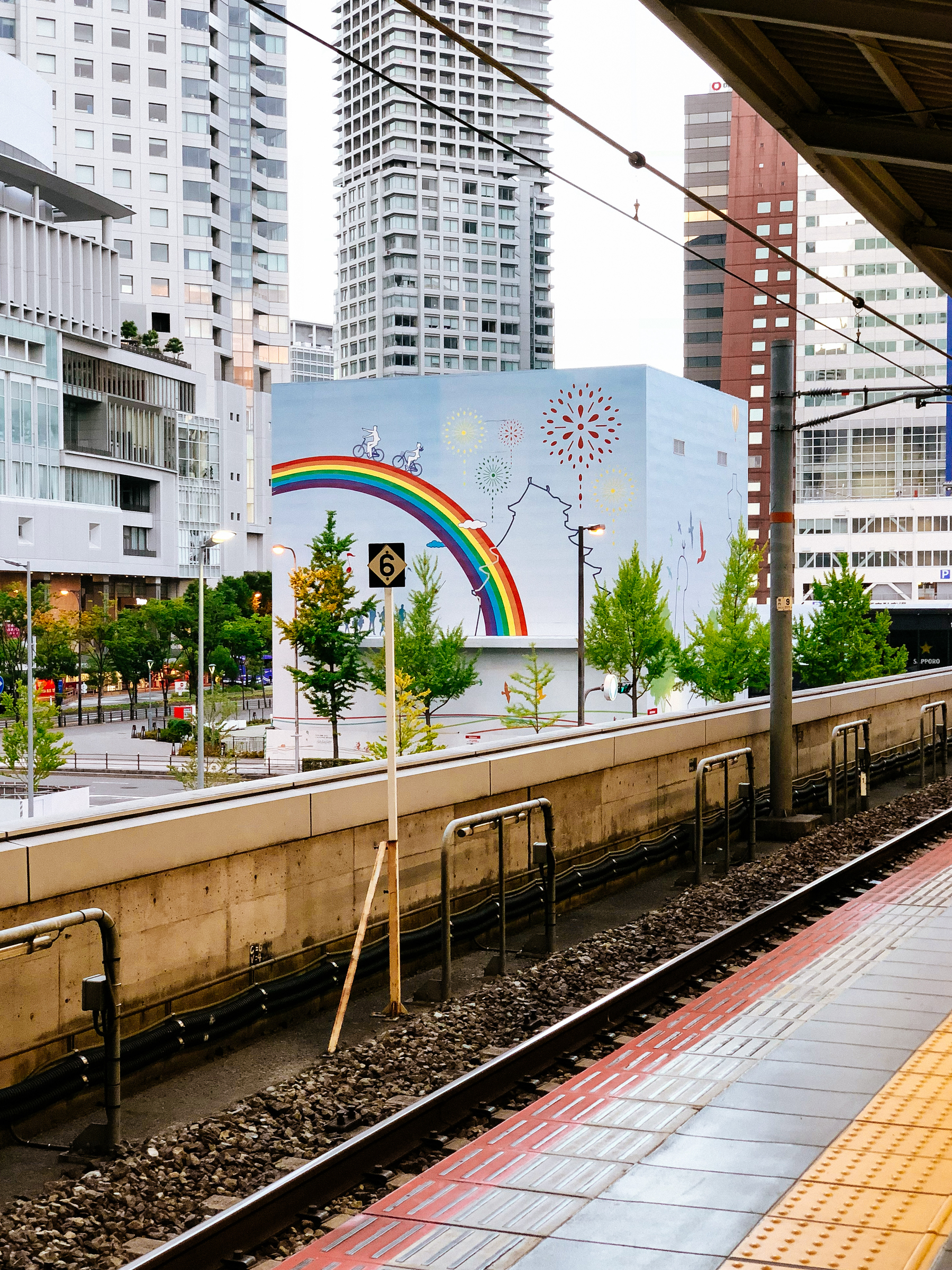 A rainbow painted in a wall, seen from a train station. 
