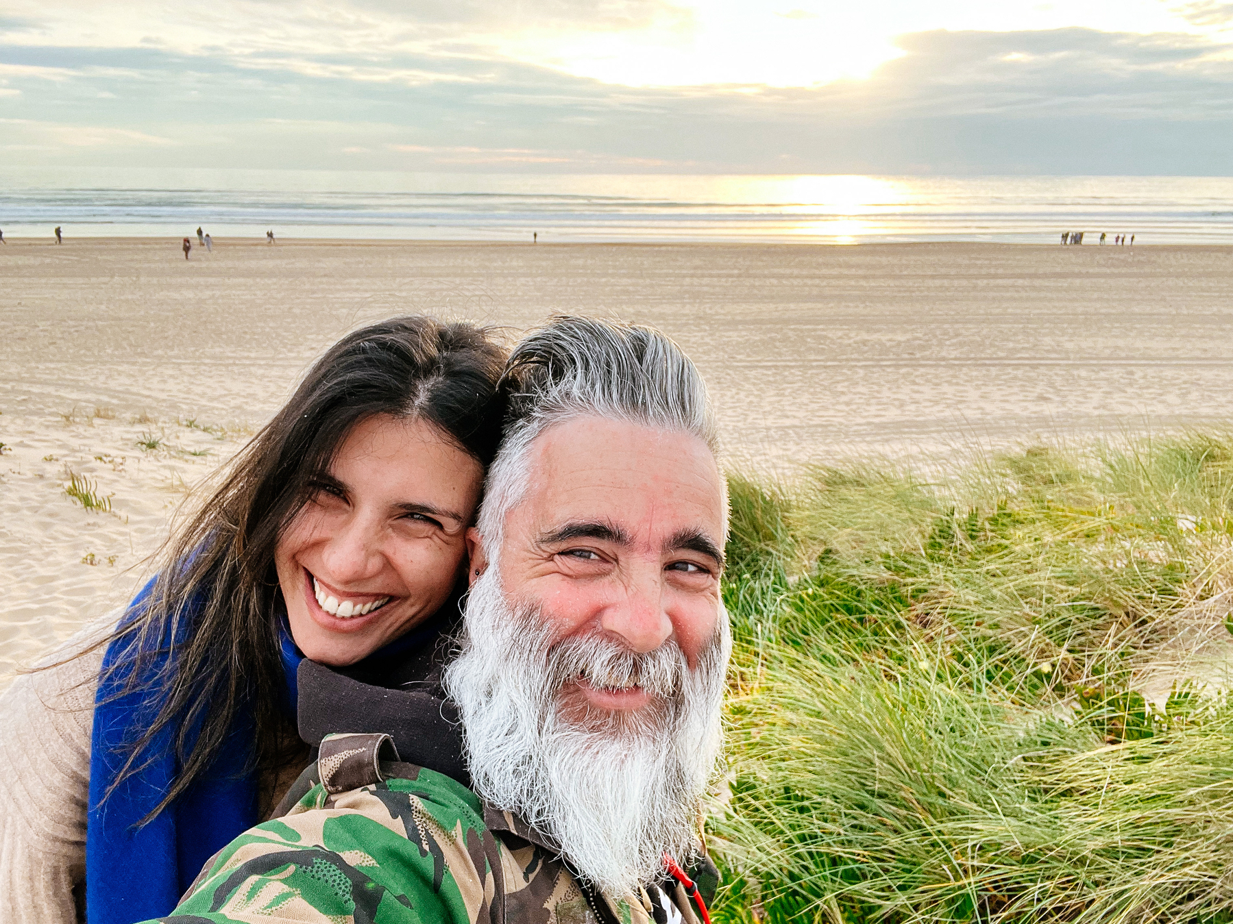 A bearded man and a very beautiful woman take a selfie, the sea in the background. 