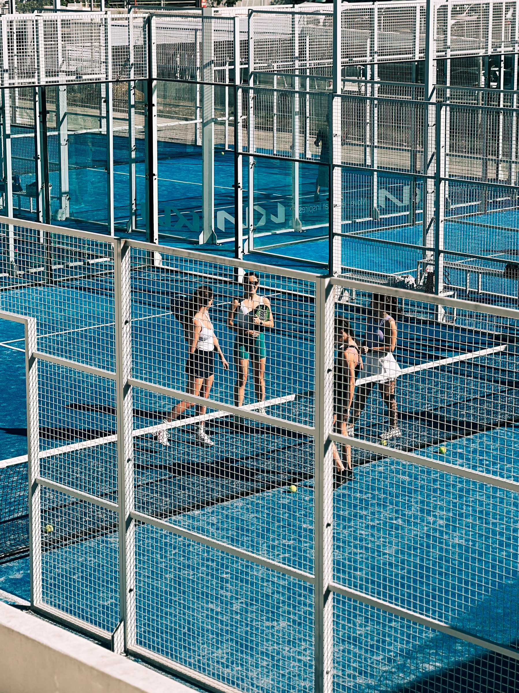 Four padel players on a blue court. 
