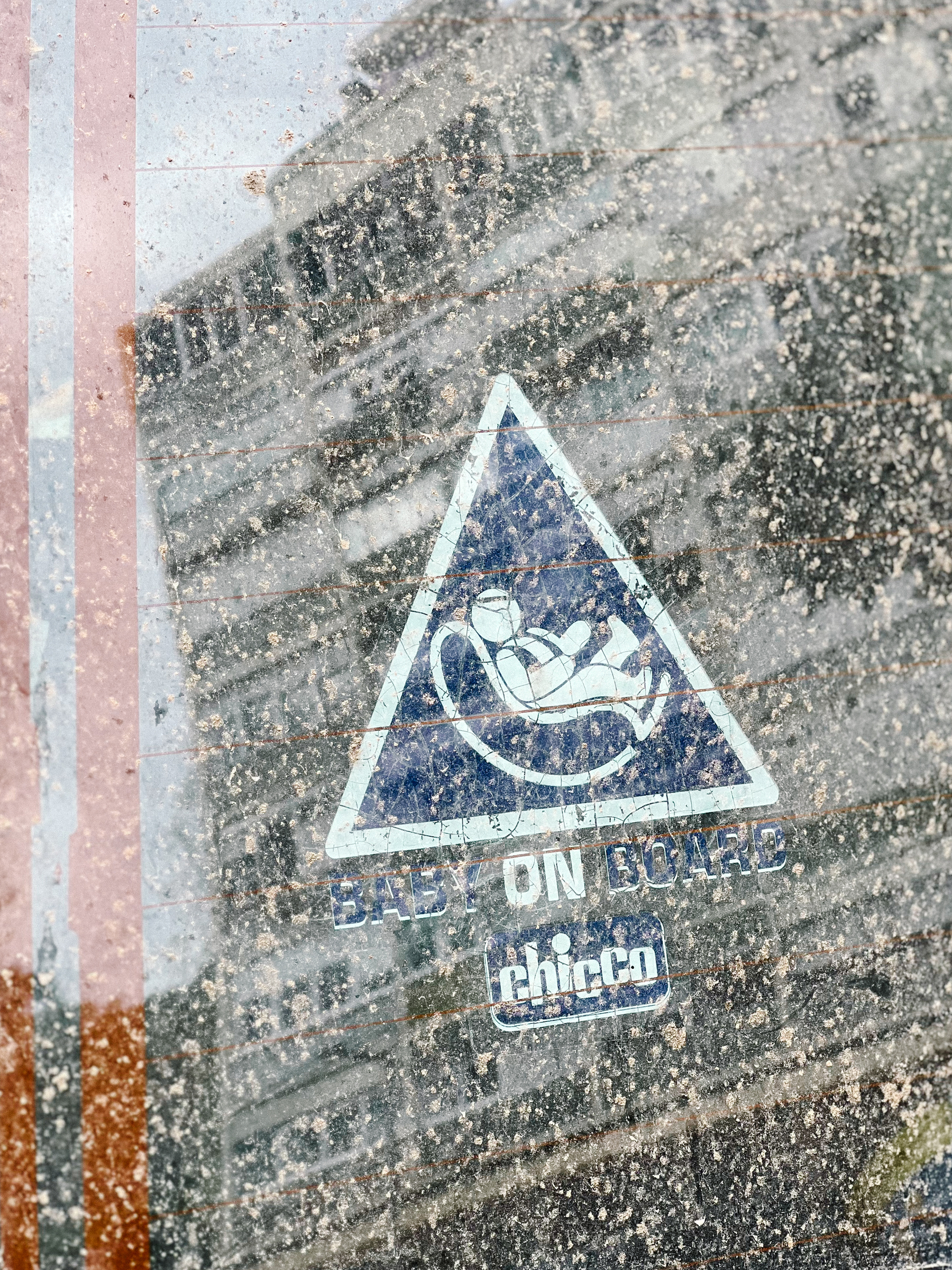 A “baby on board” sticker, on a very dirty window. 