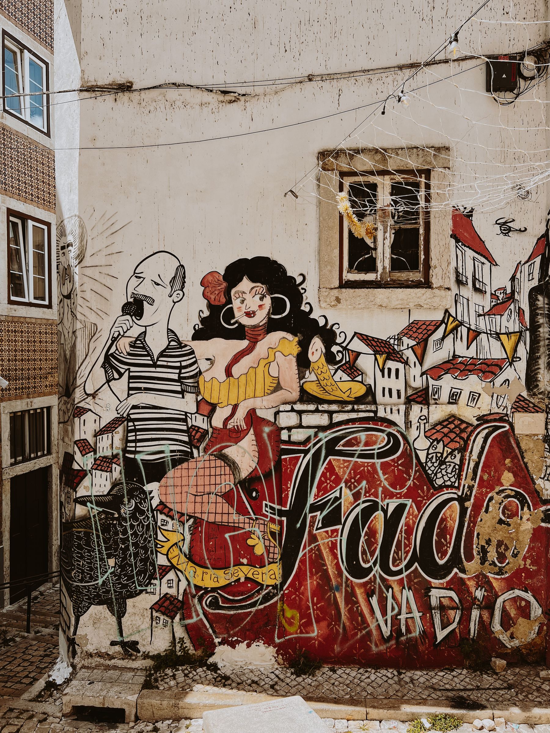 Graffiti on a building. A man, a woman, the words “Fado Vadio”. 