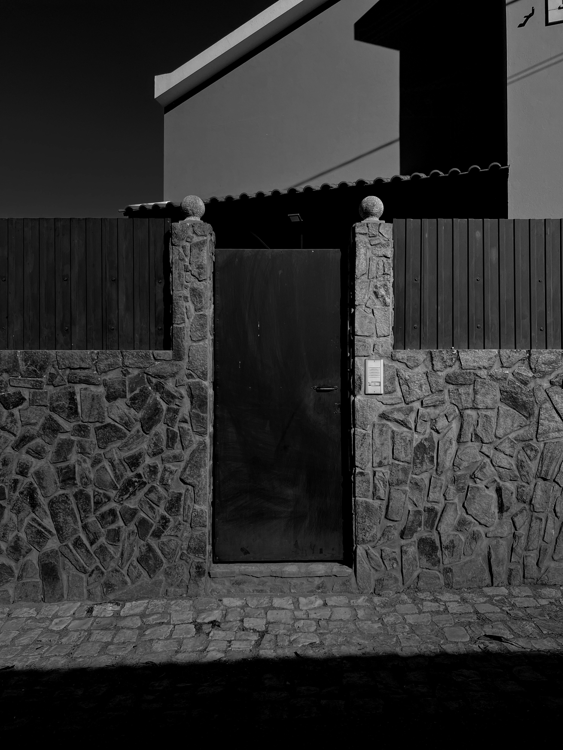 Black and white photo, a door, a stone wall. 