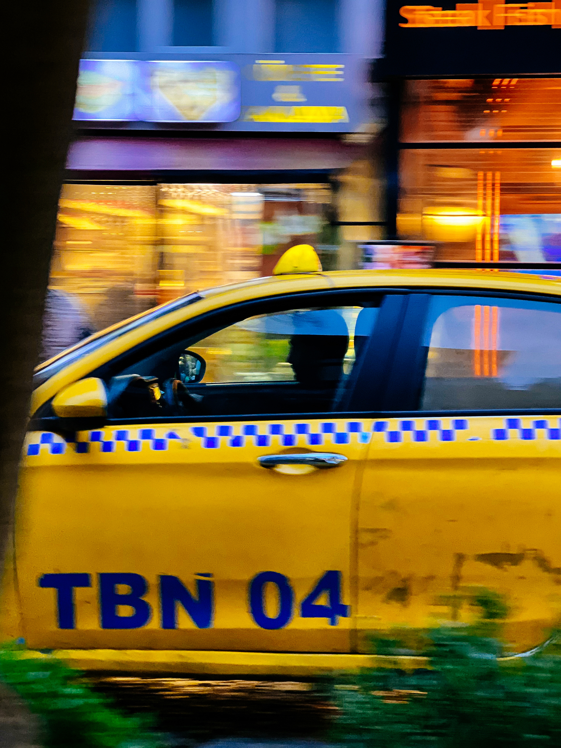A yellow taxi drives by.