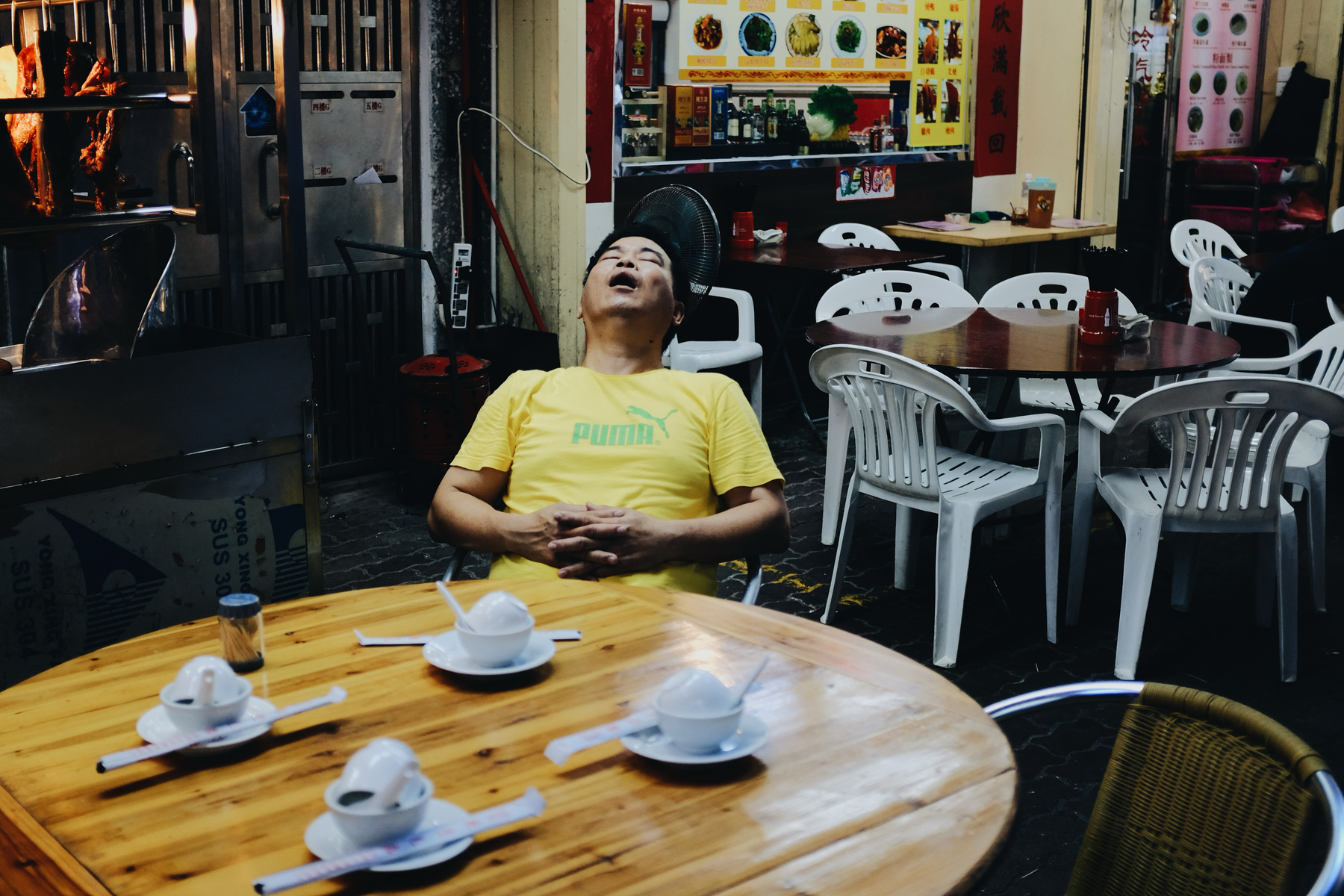 A man sleeps while sitting at a restaurant table. 