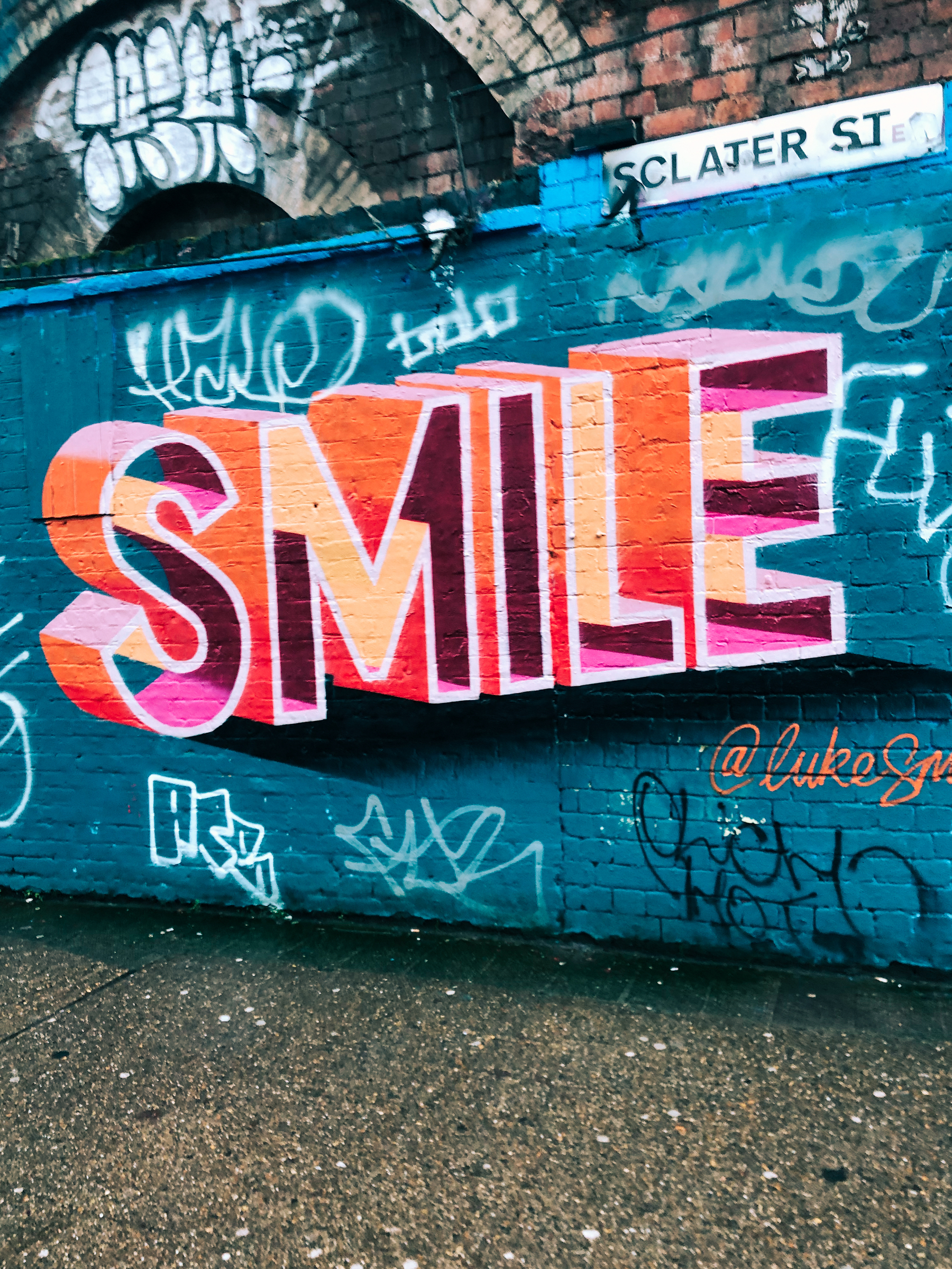 Graffitied wall. The word “Smile”.