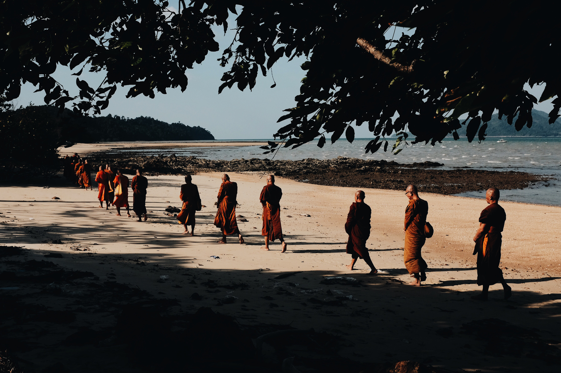 Monks walking on a beach. 