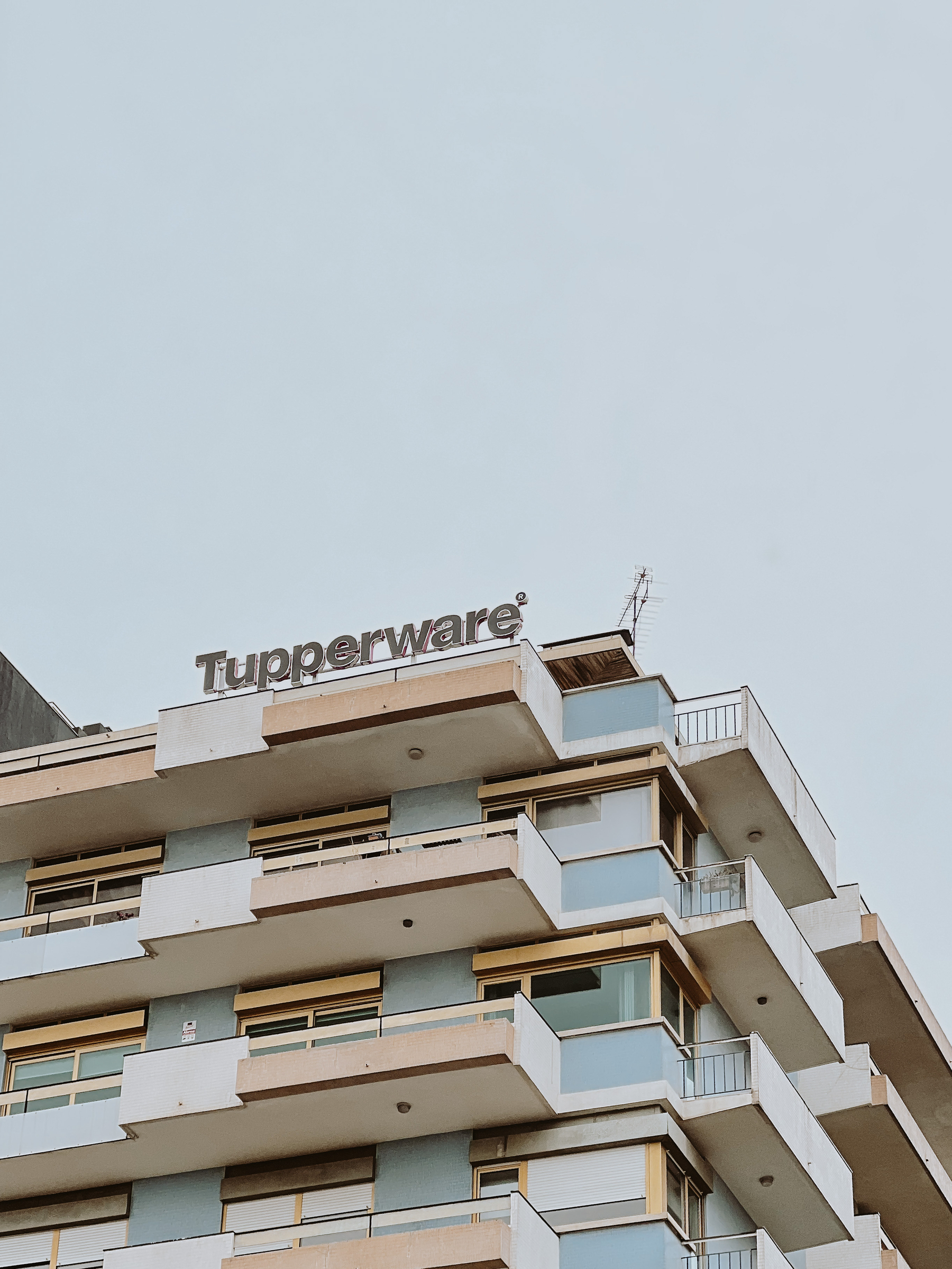 A Tupperware sign on the roof of a building.