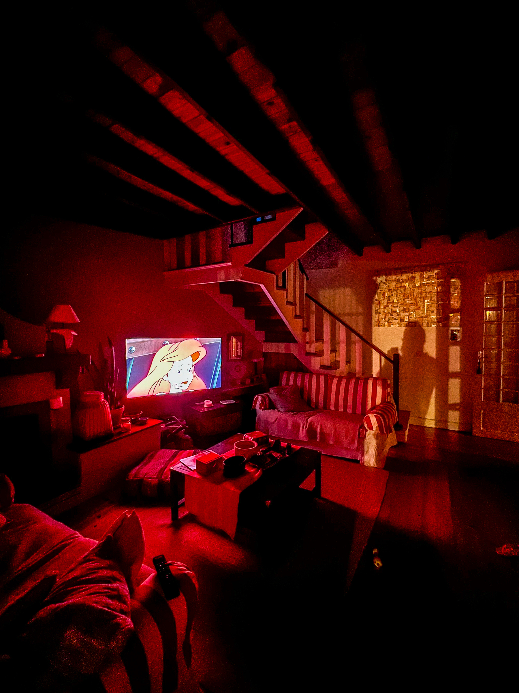 Red lit room, with cartoons on TV. 
