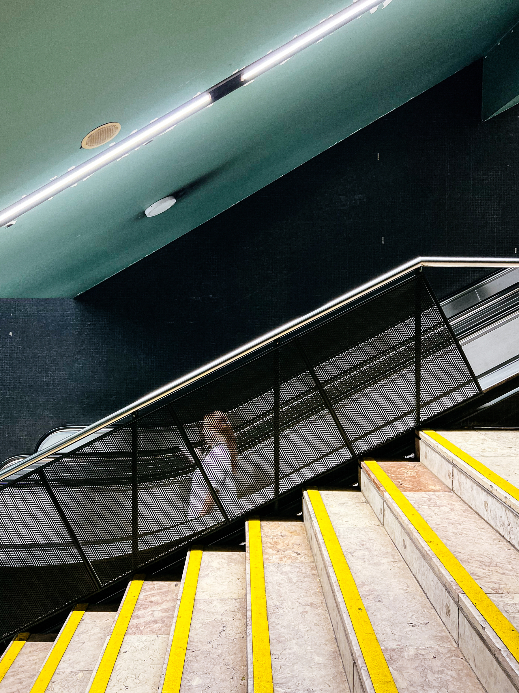 A woman goes down an escalator, underground. 