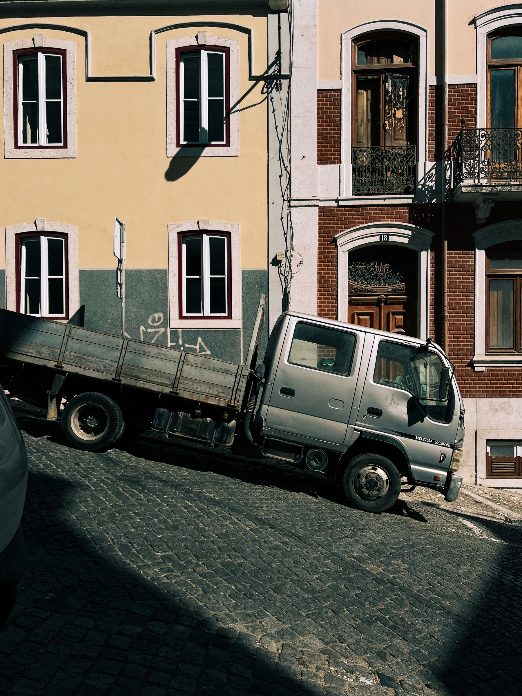 A truck is parked on a very steep street.