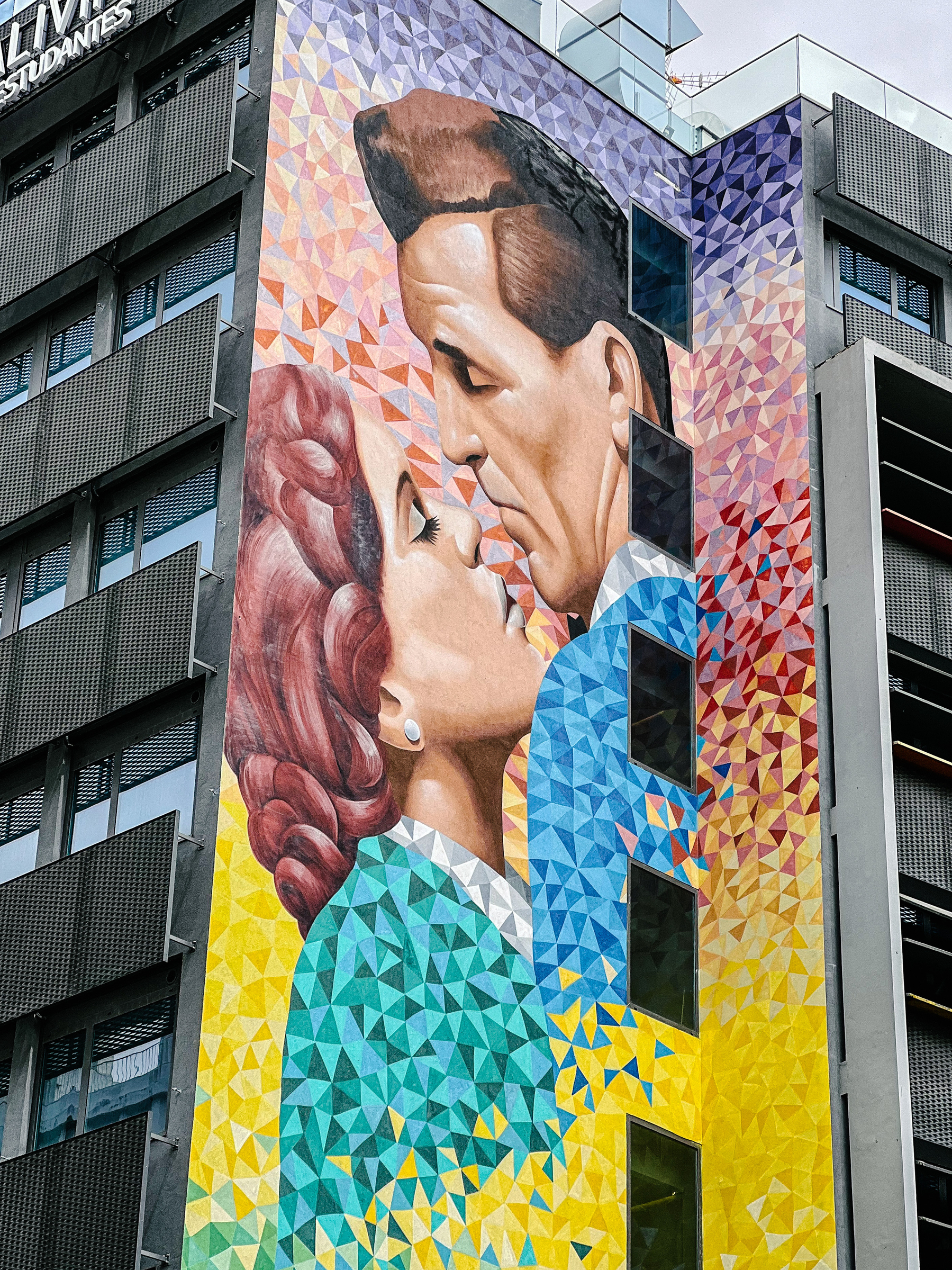 Street art piece, on the side of a building. A couples kissing. 