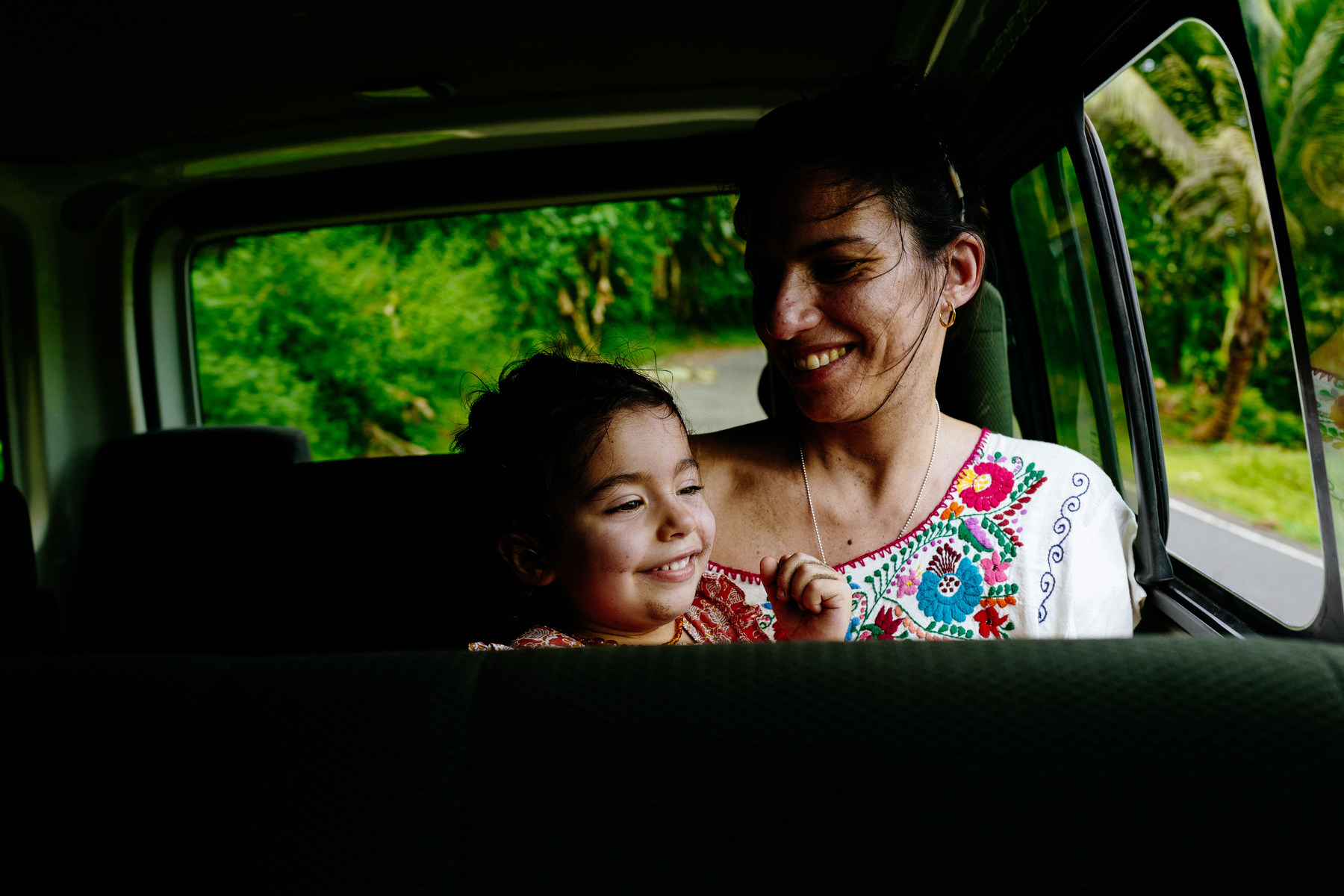 A girl and a woman smile, Riding in the back of a van. 