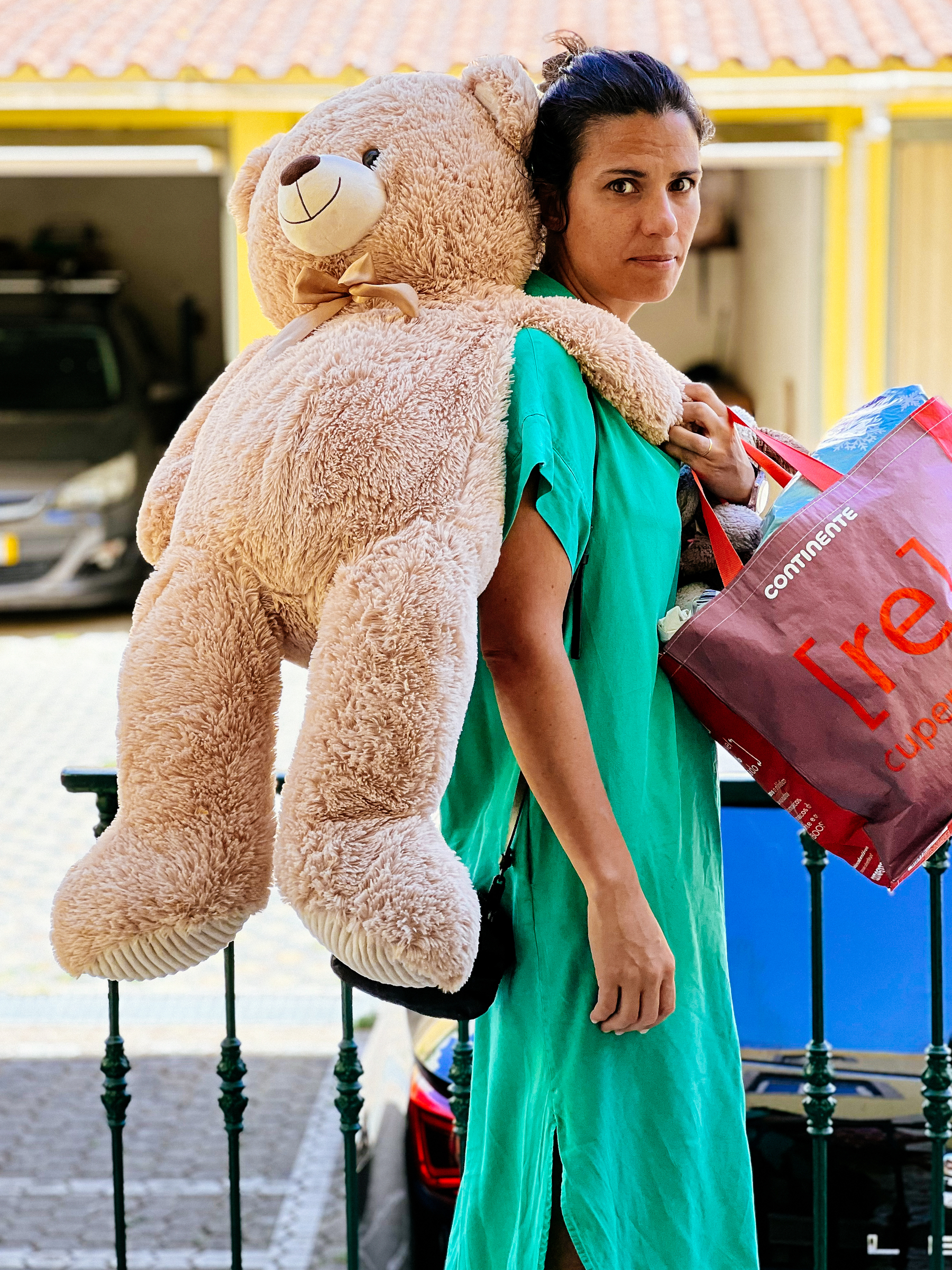 a woman carries a giant teddy bear.