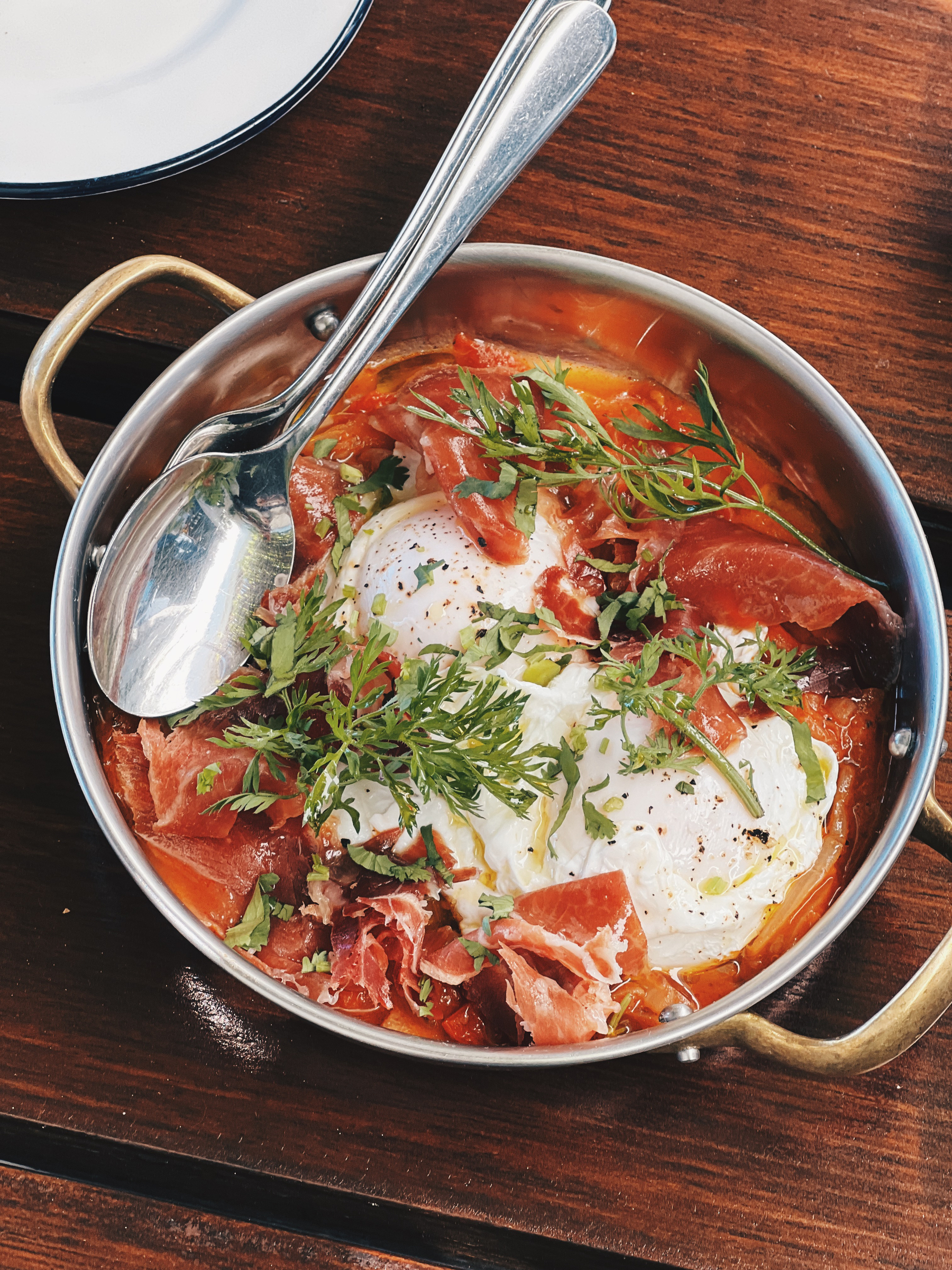 A pan with poached eggs and prosciutto.