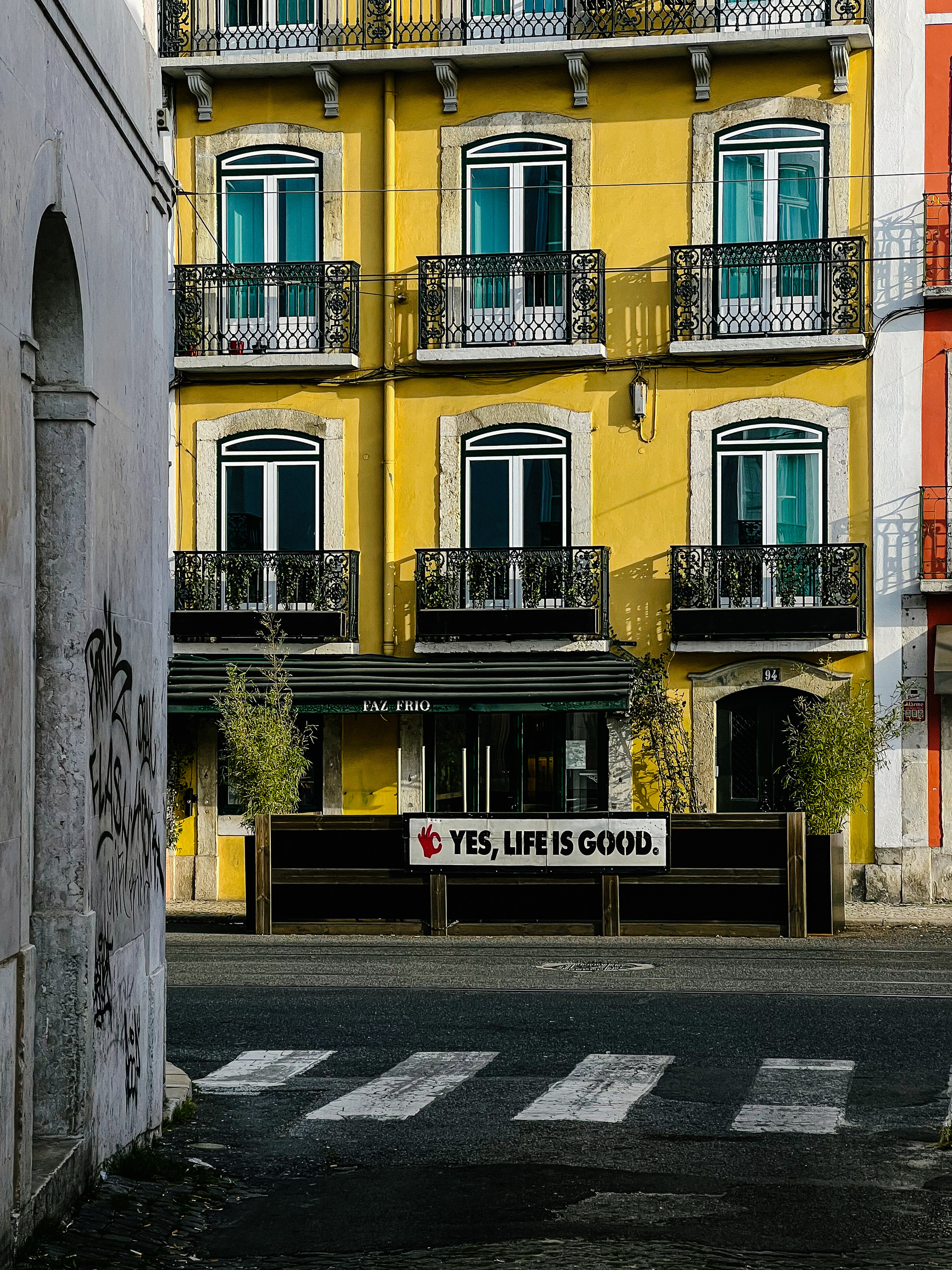 A yellow building with a sign that says “Yes, life is good”. 