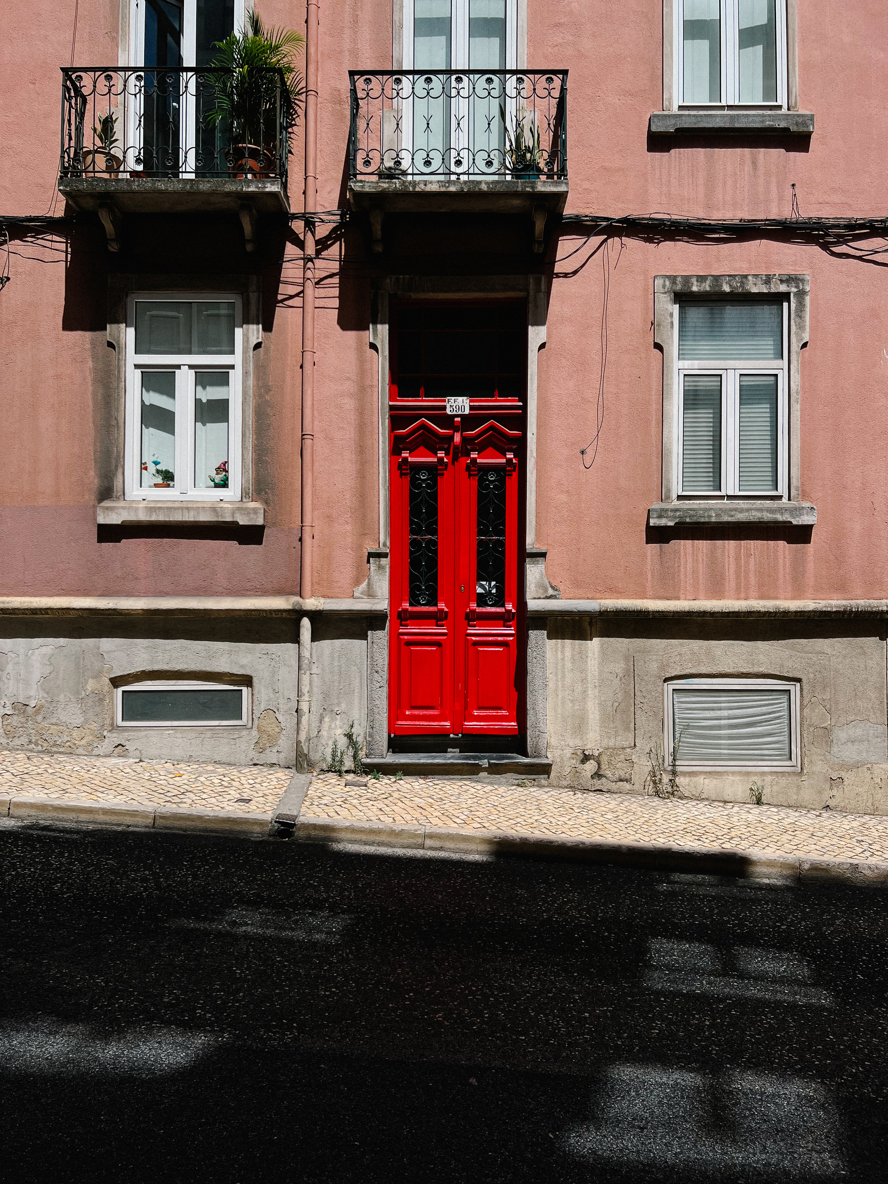 A red door, in a pink building. 