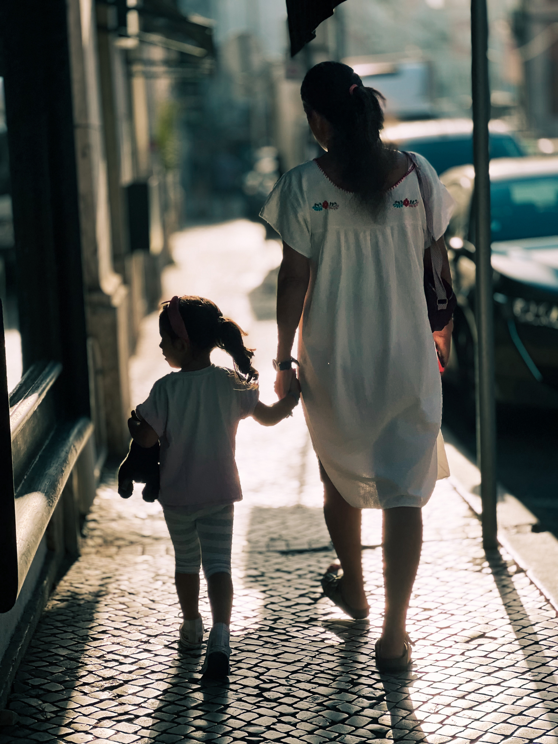 A girl and her mom walking, holding hands. 