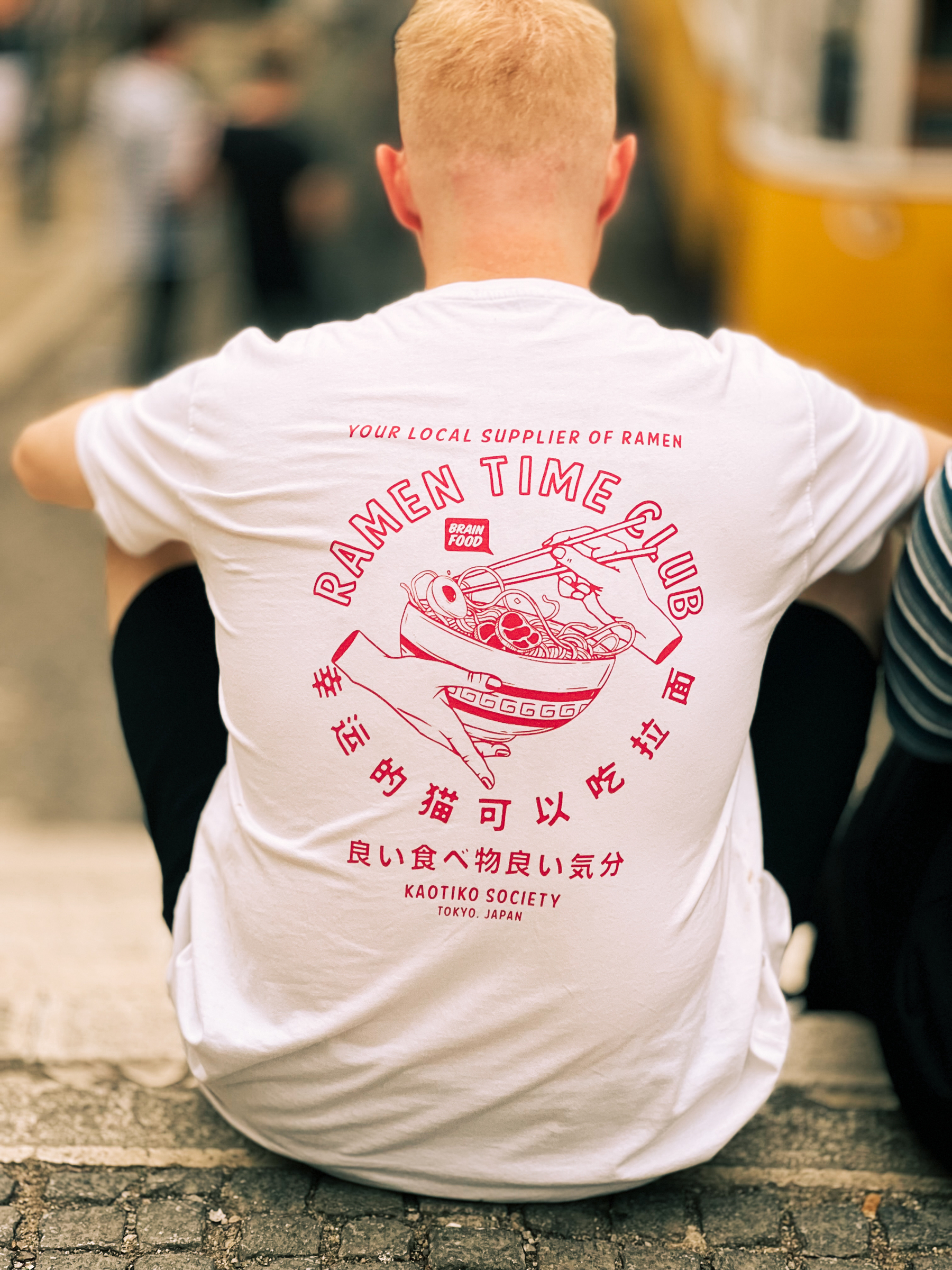A “Ramen Time Club” t-shirt. The owner is sitting down on the ground, his back to us. 