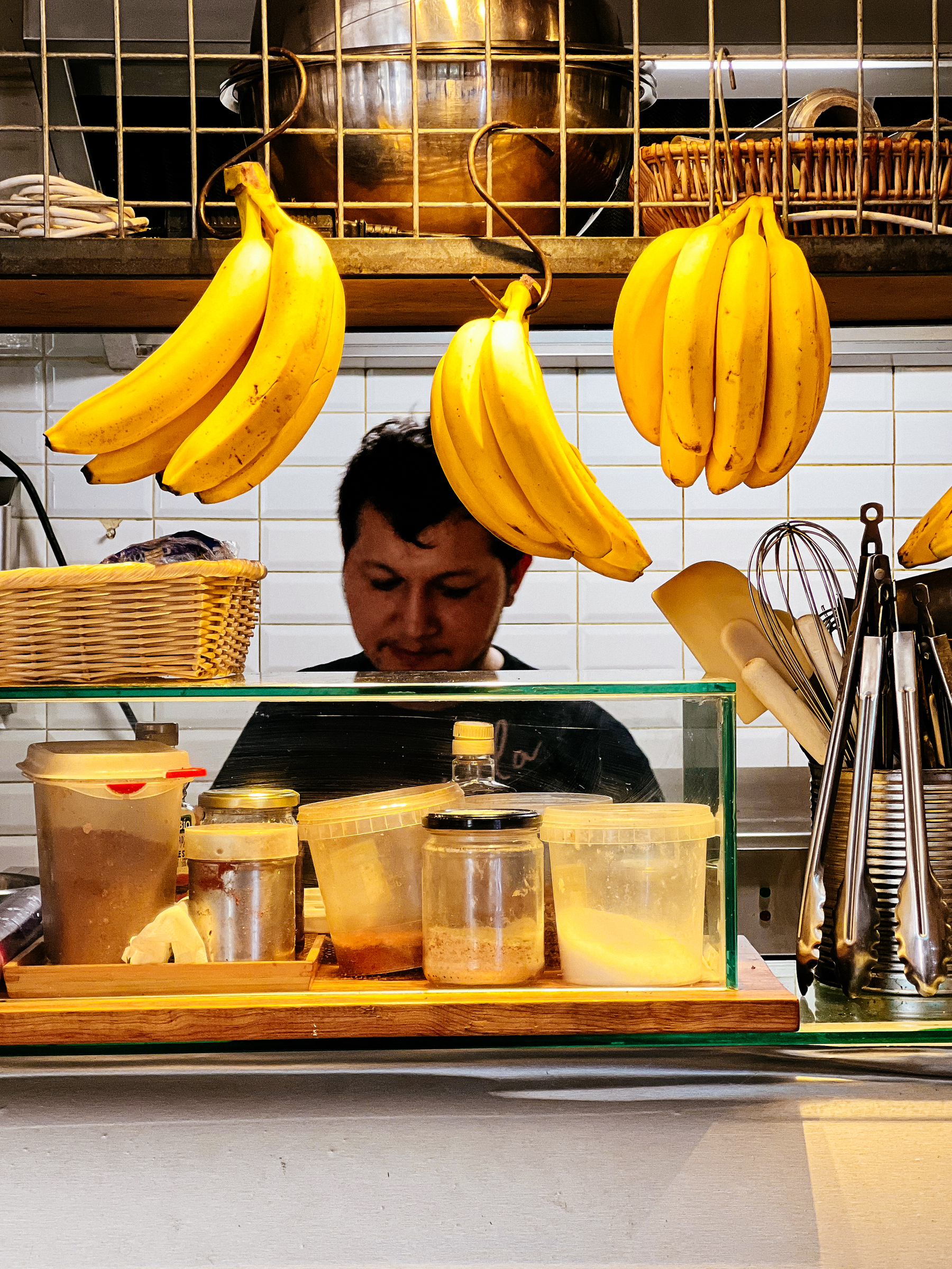 A waiter at a cafe, behind some bananas. 