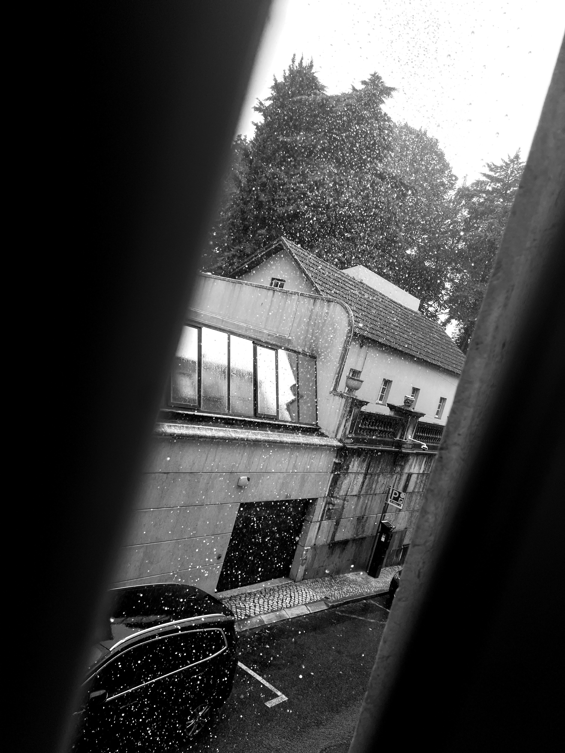 Black and white photo, rain pouring outside. 