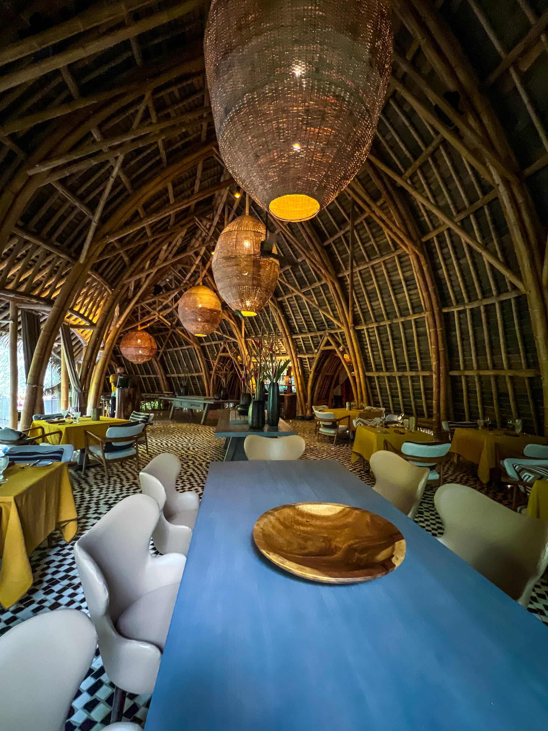 A restaurant made of bamboo, with a huge ceiling, and gigantic wicker lamps. 