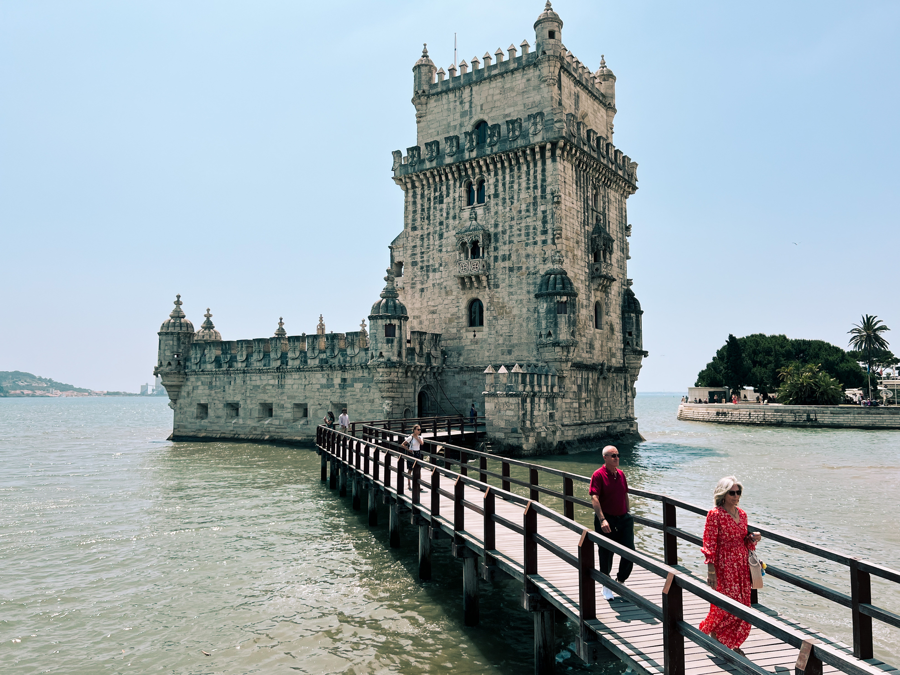 Tourists leave a castle like tower, on the river. 