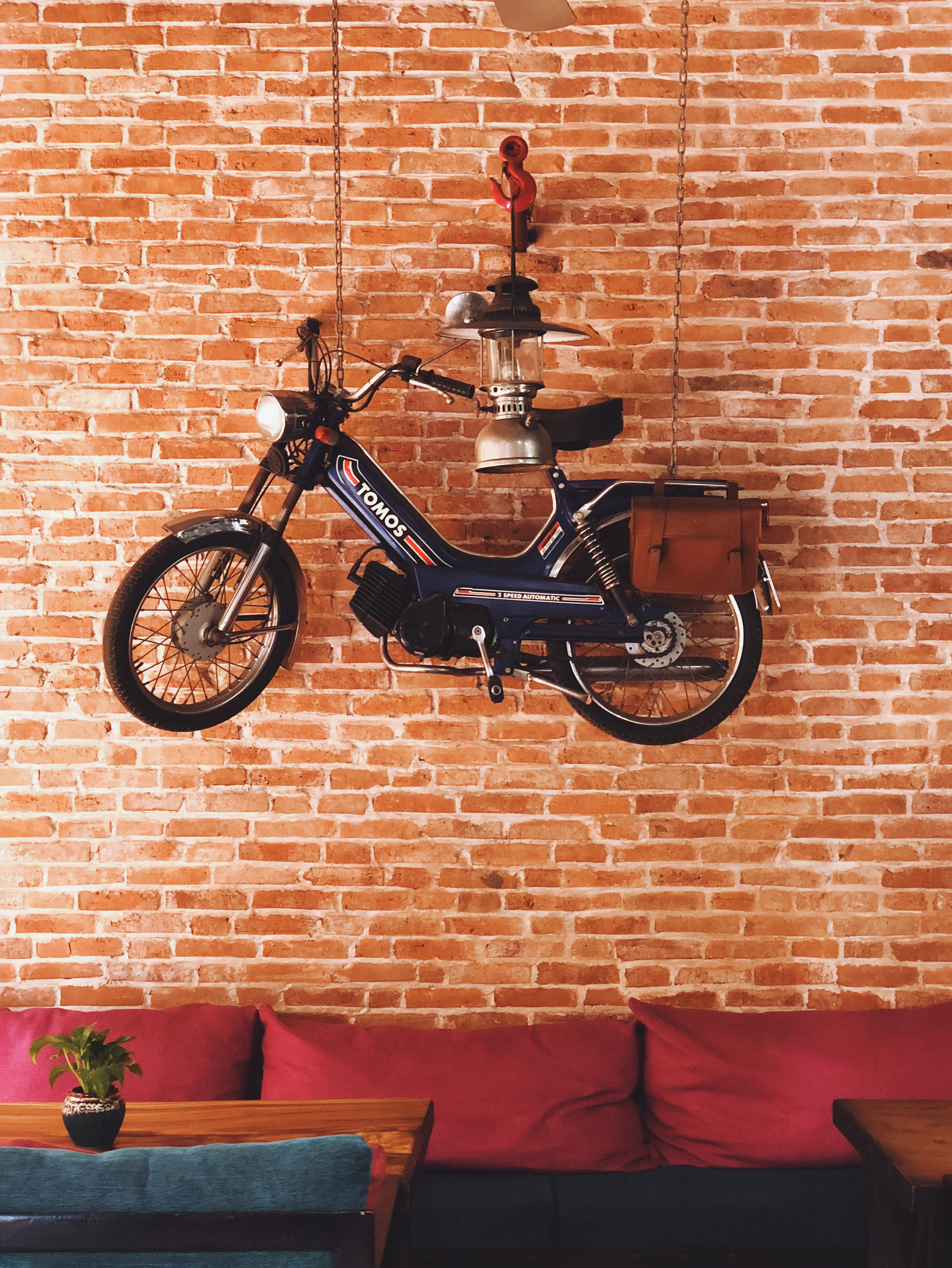 A moped hangs from a brick wall. 