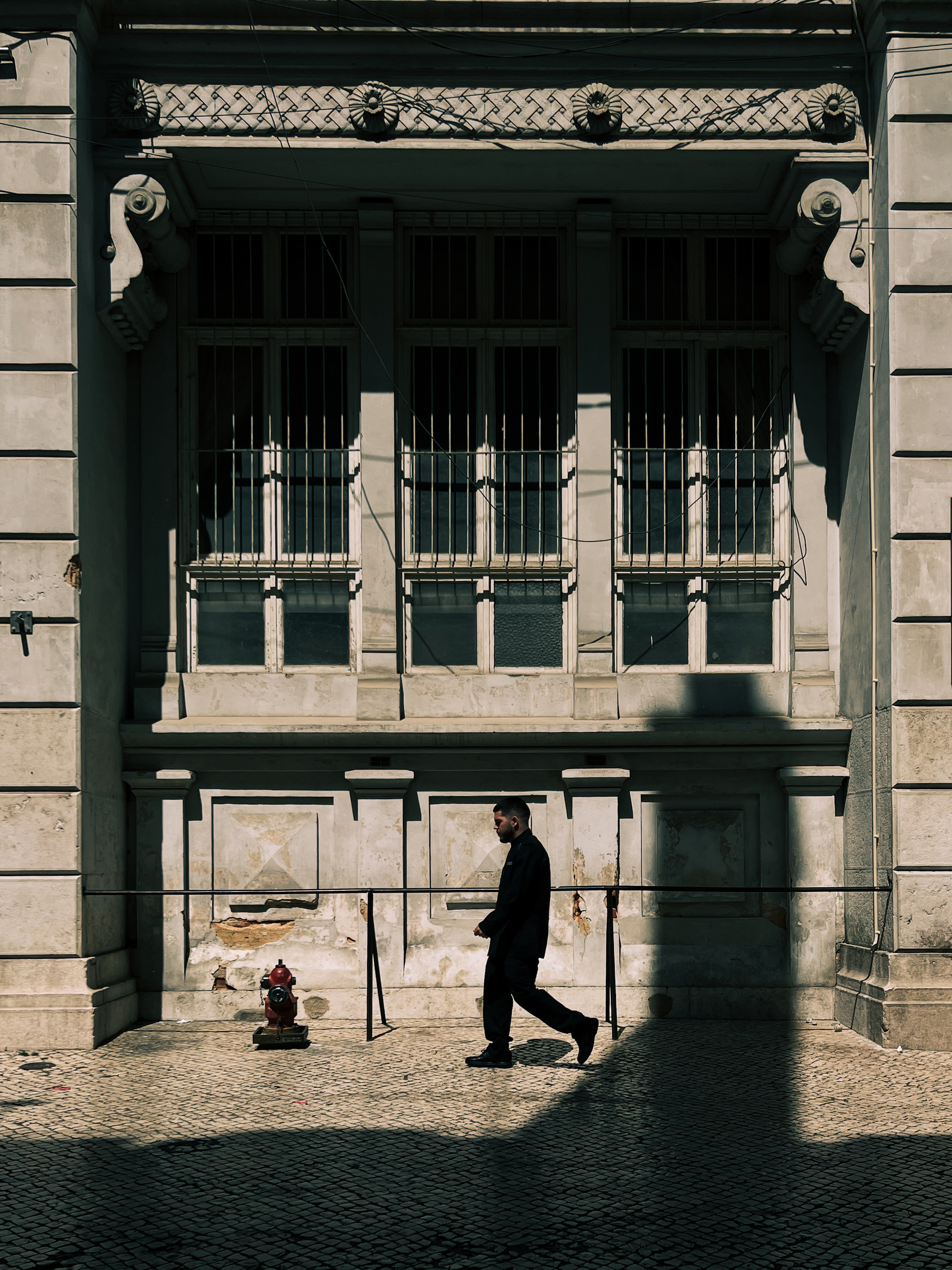 A man walks by a classic building.
