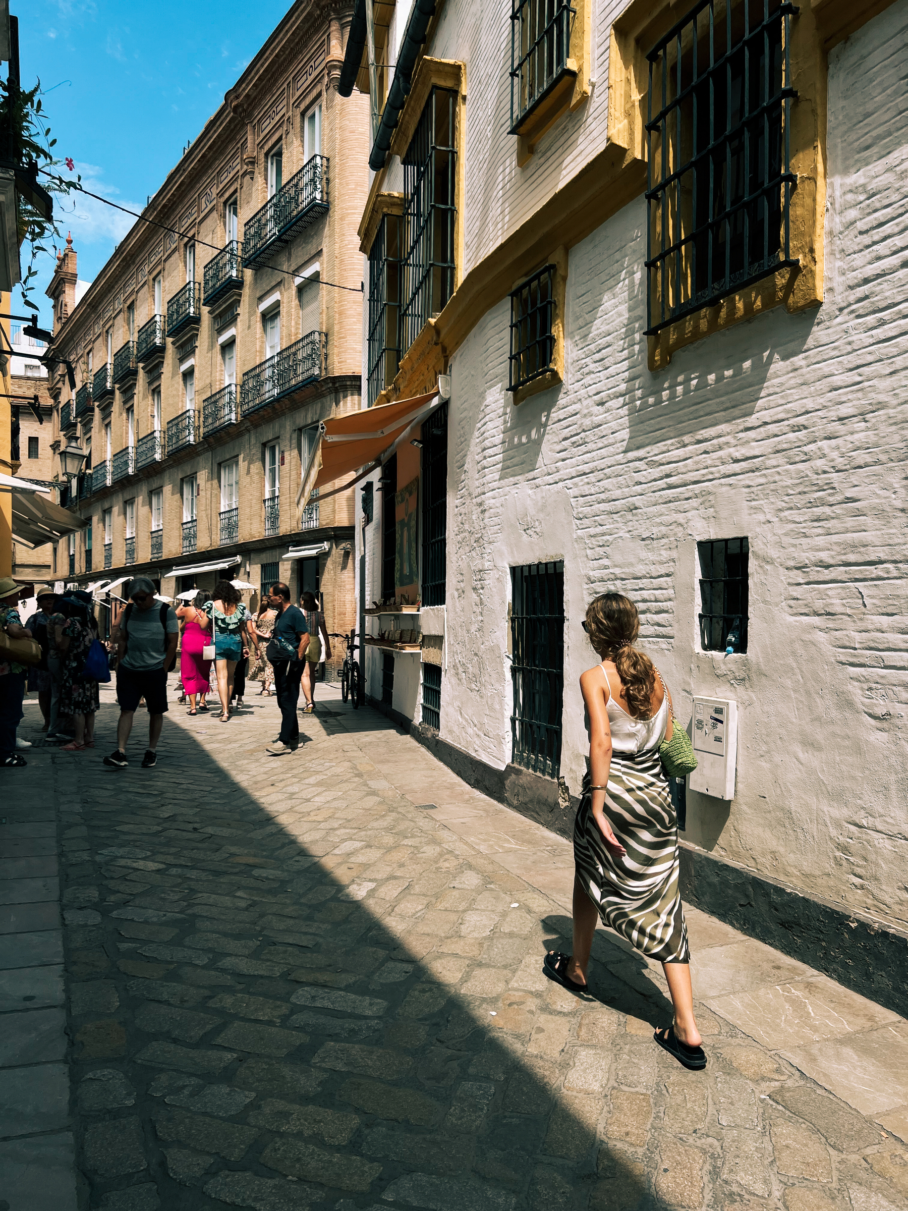 Tourists walking in Santa Cruz, a classic neighborhood in Sevilla. Narrow streets and classic buildings. 