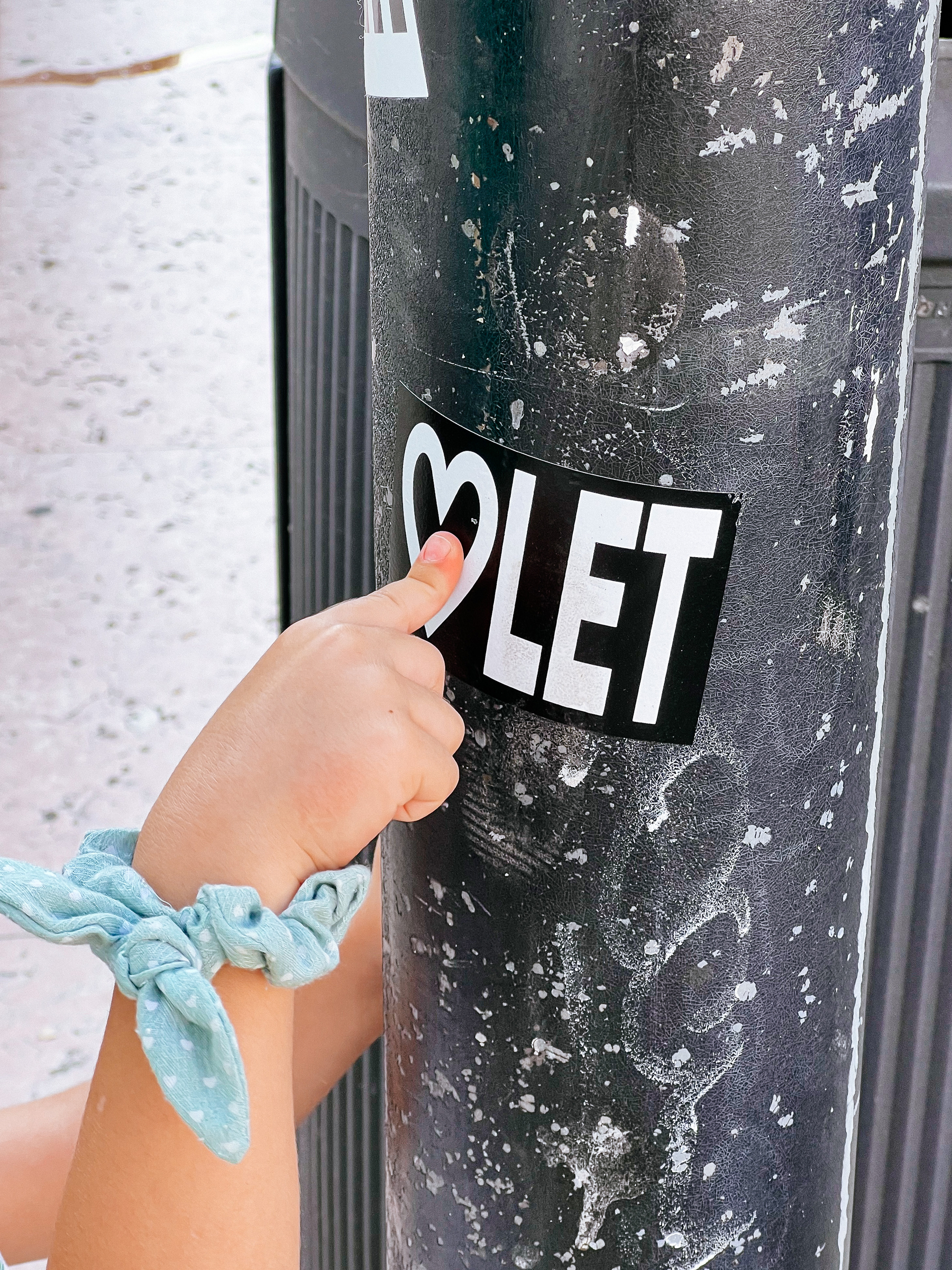 A hand points at a sticker in a pole. 