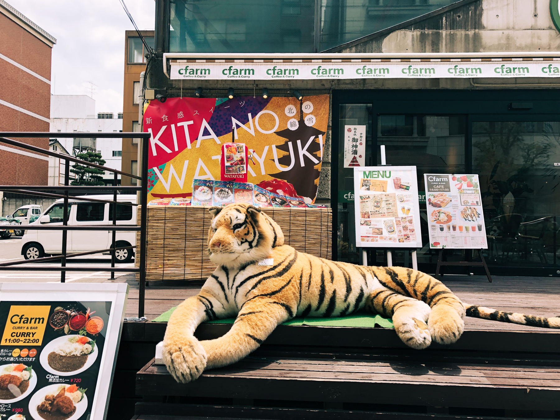 A big plush tiger sitting outside a restaurant. 