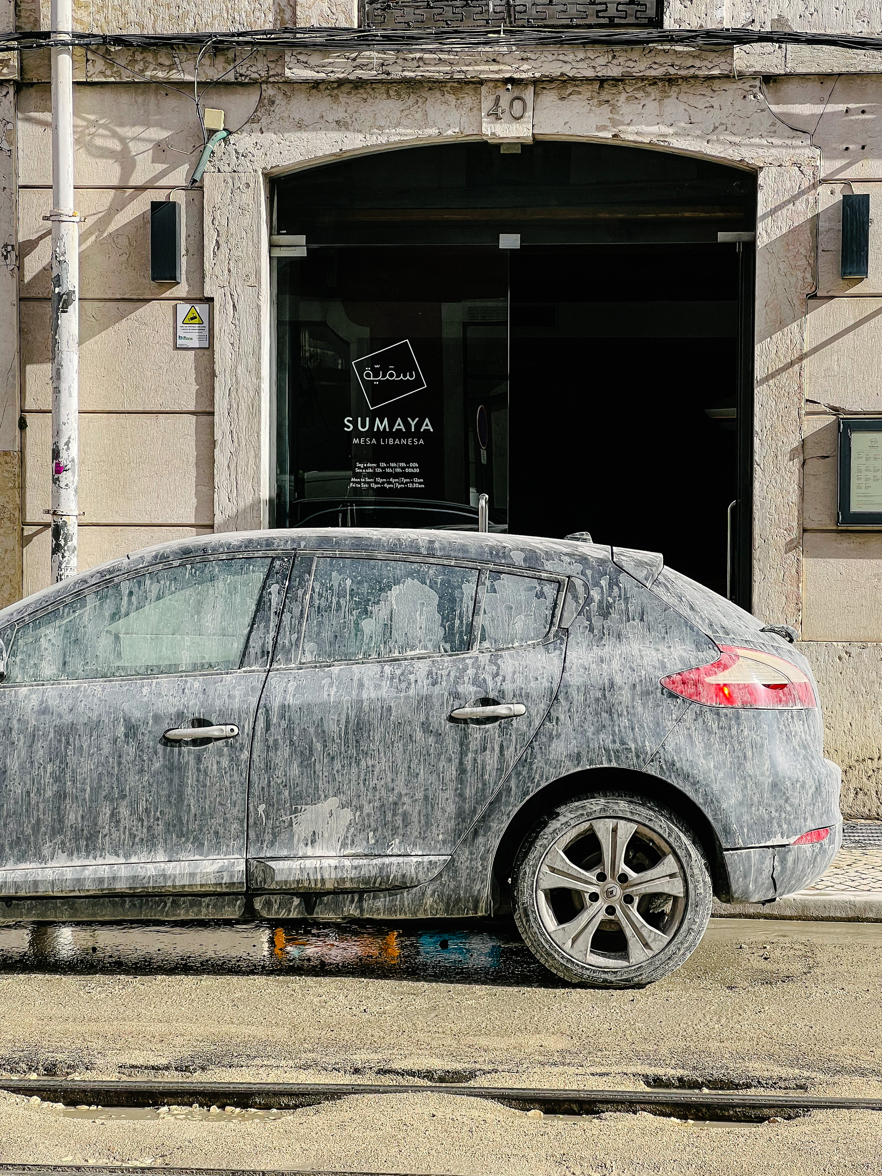 A car covered in mud that was splashed onto it from construction work going on in the street. 