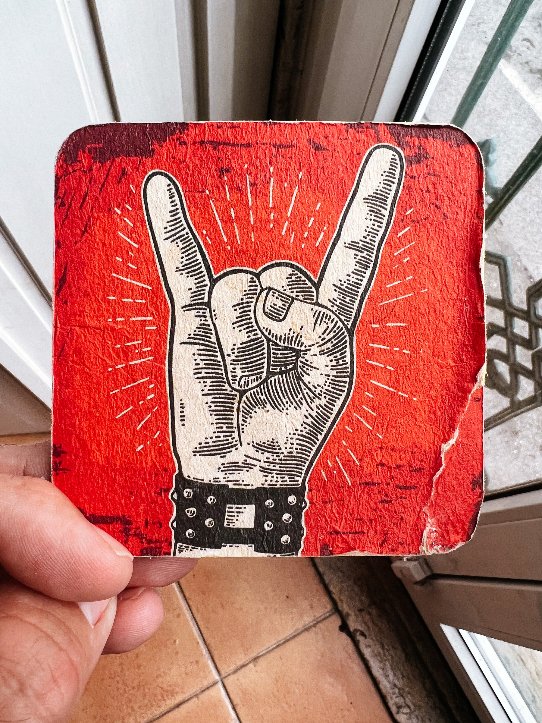 A beer coaster with a 🤘🏼drawing 