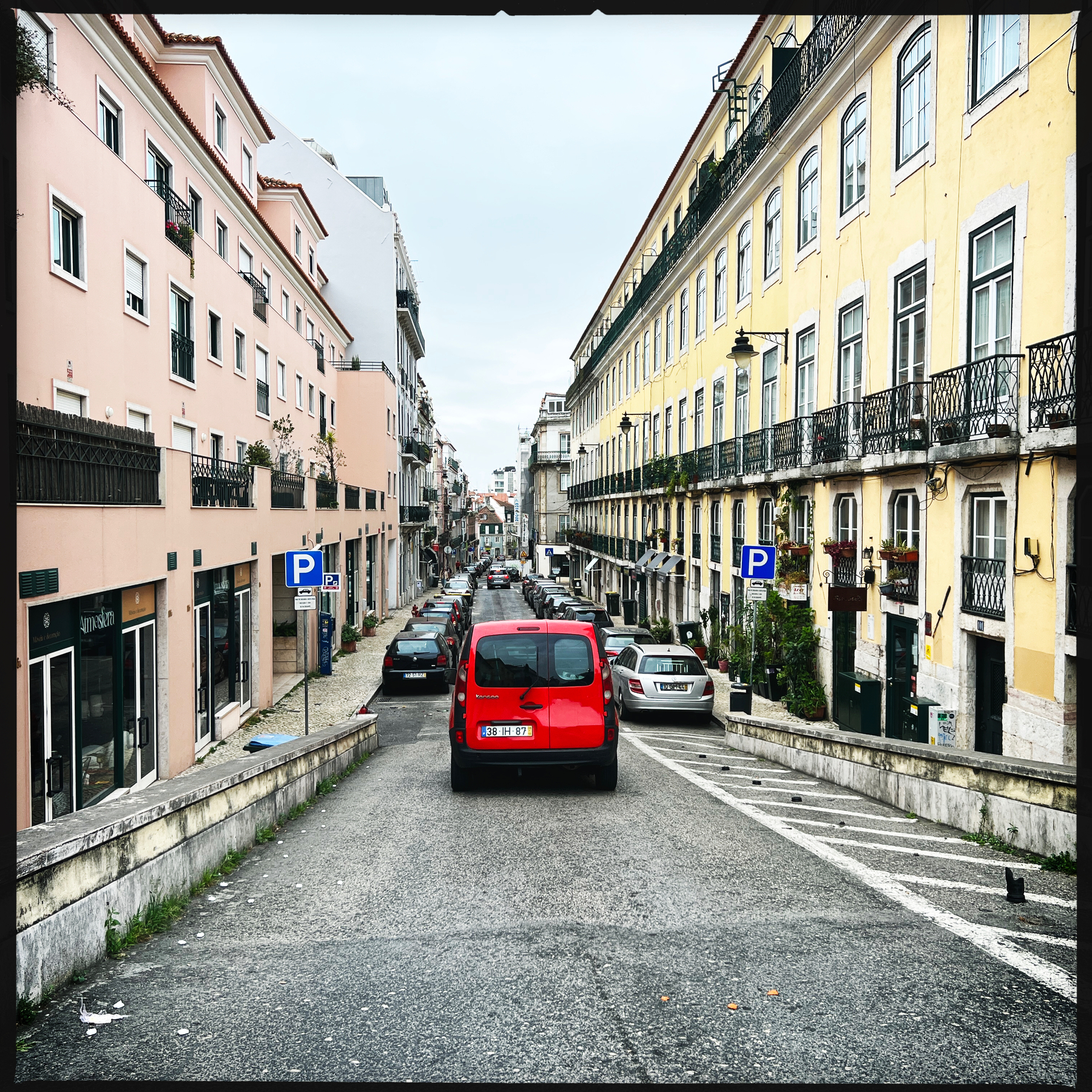 A red car in a classic Lisbon street. 