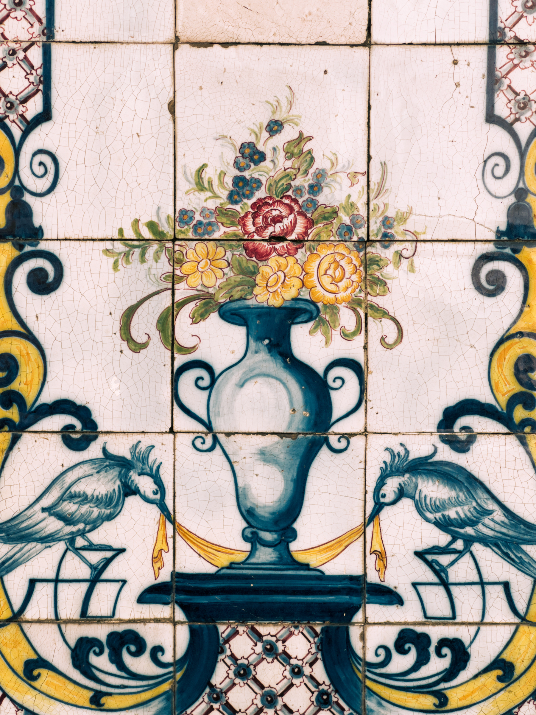 Detail of a tiled wall. A vase with flowers.