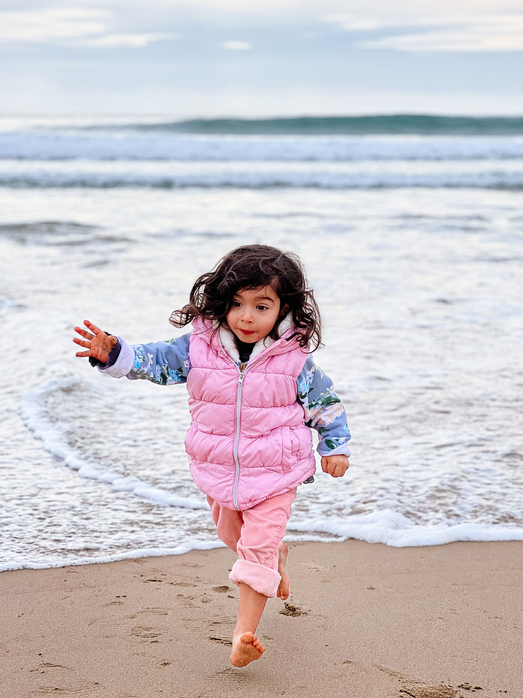 A girl runs towards us, escaping the sea water. 