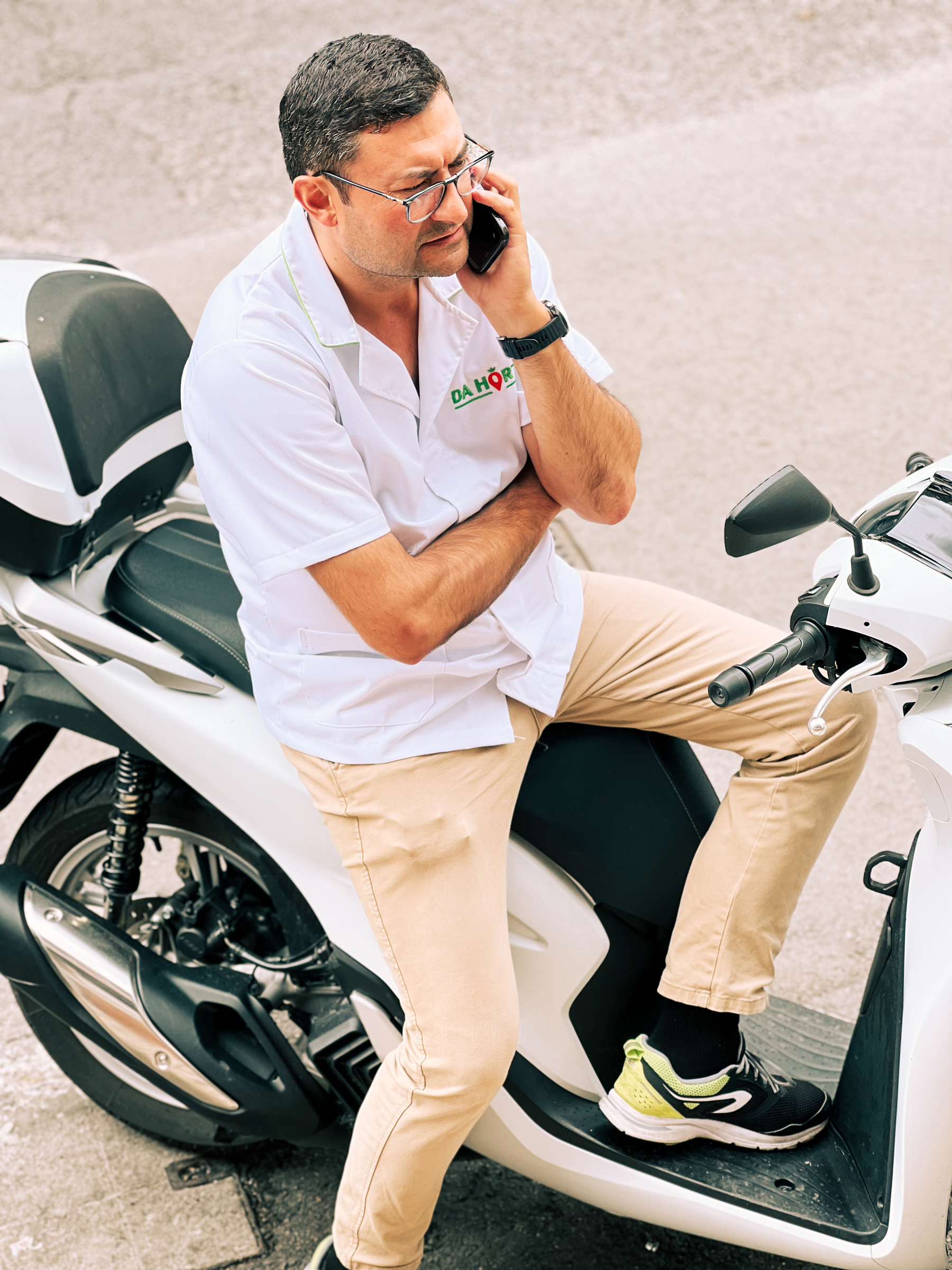 A man sits on his scooter, on the phone. 