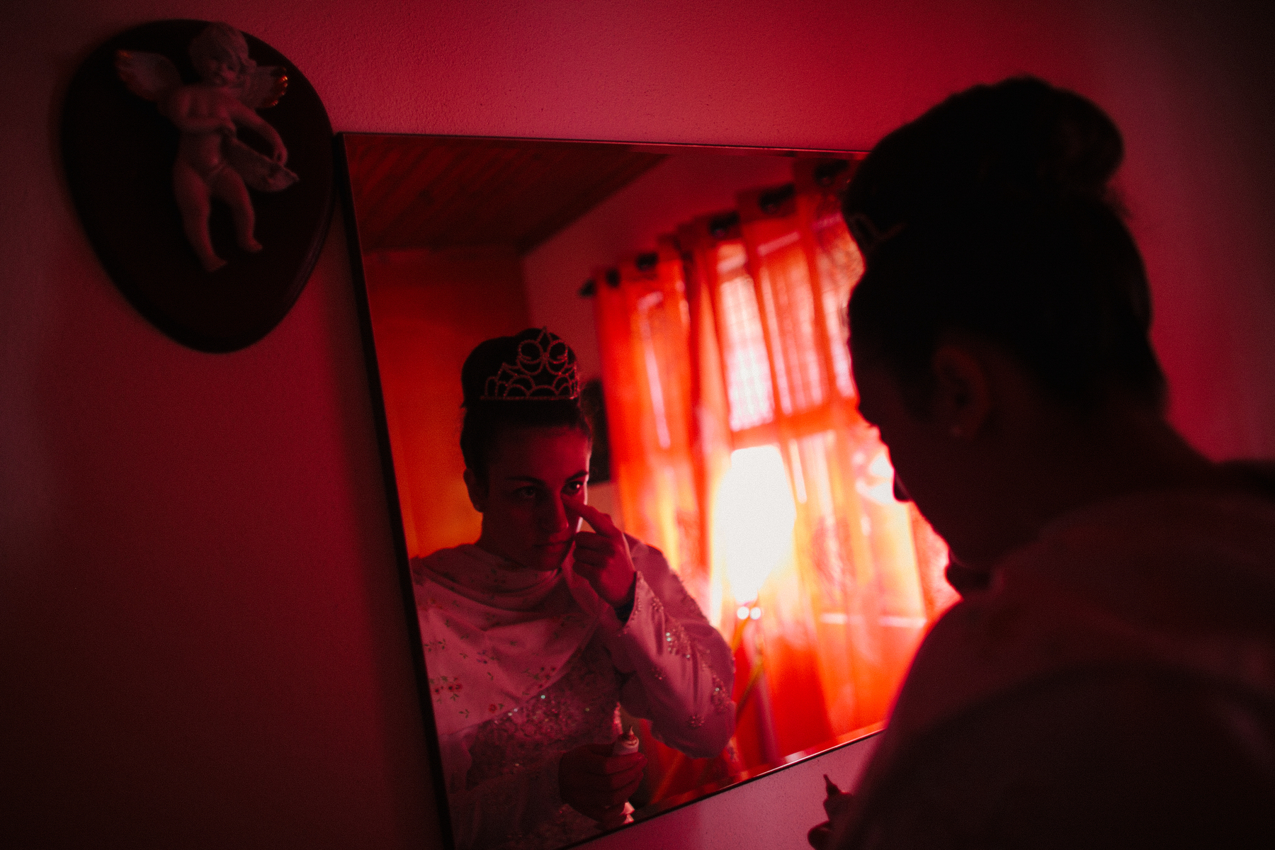 A girl applies makeup on a red lit room.