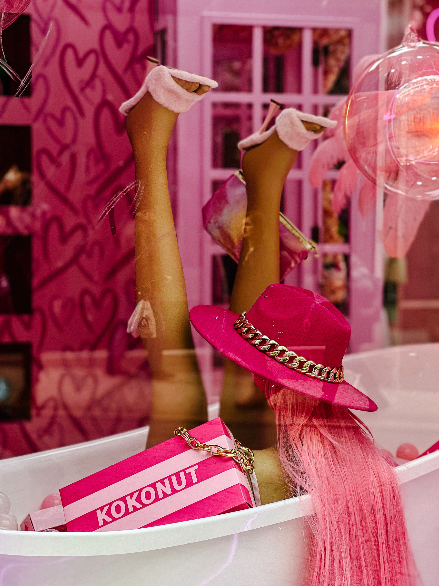 A mannequin, with a pink hat, in a bathtub, in a pink room. Pink everywhere!