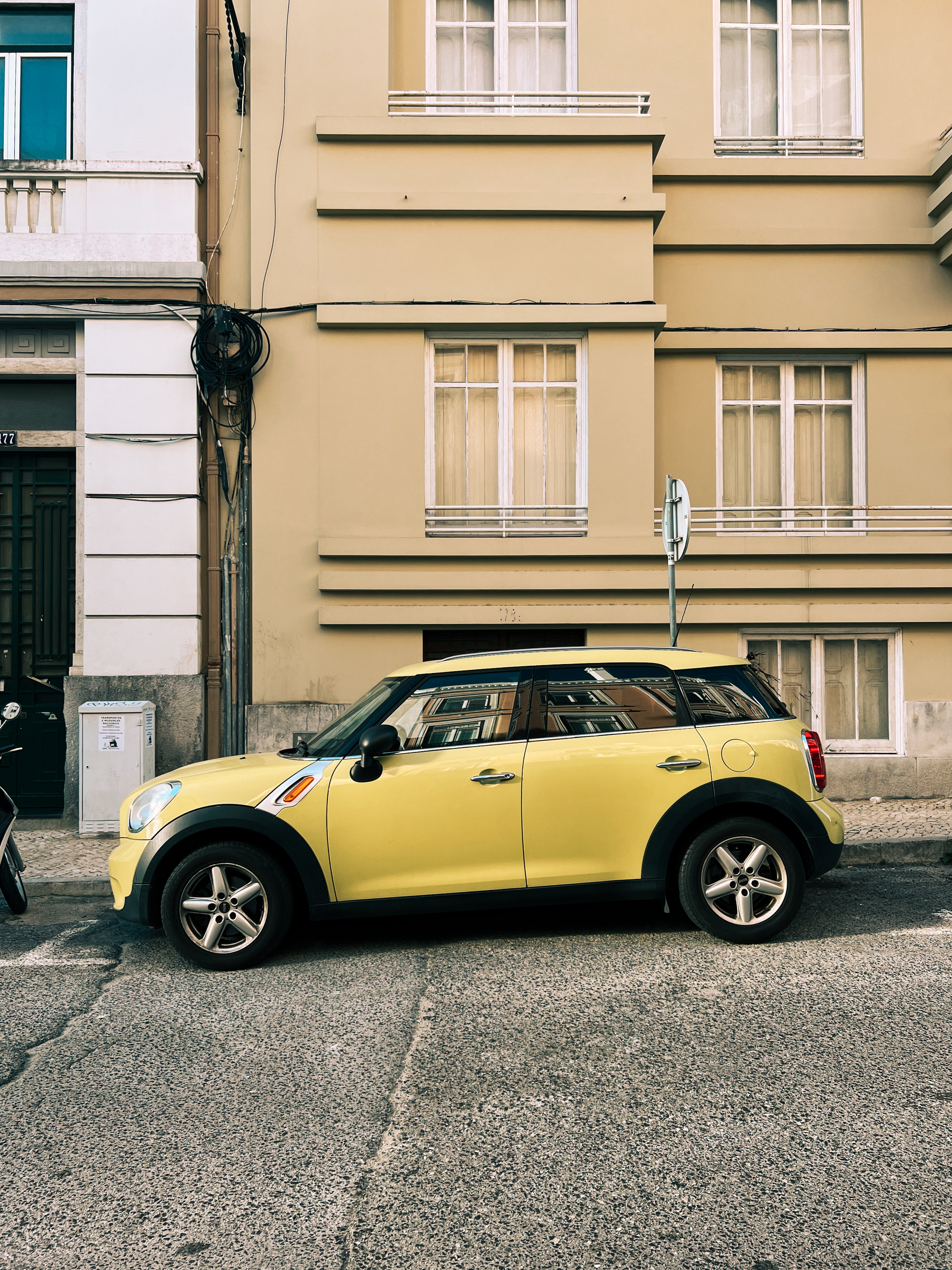A yellow car parked in front of a yellow building.