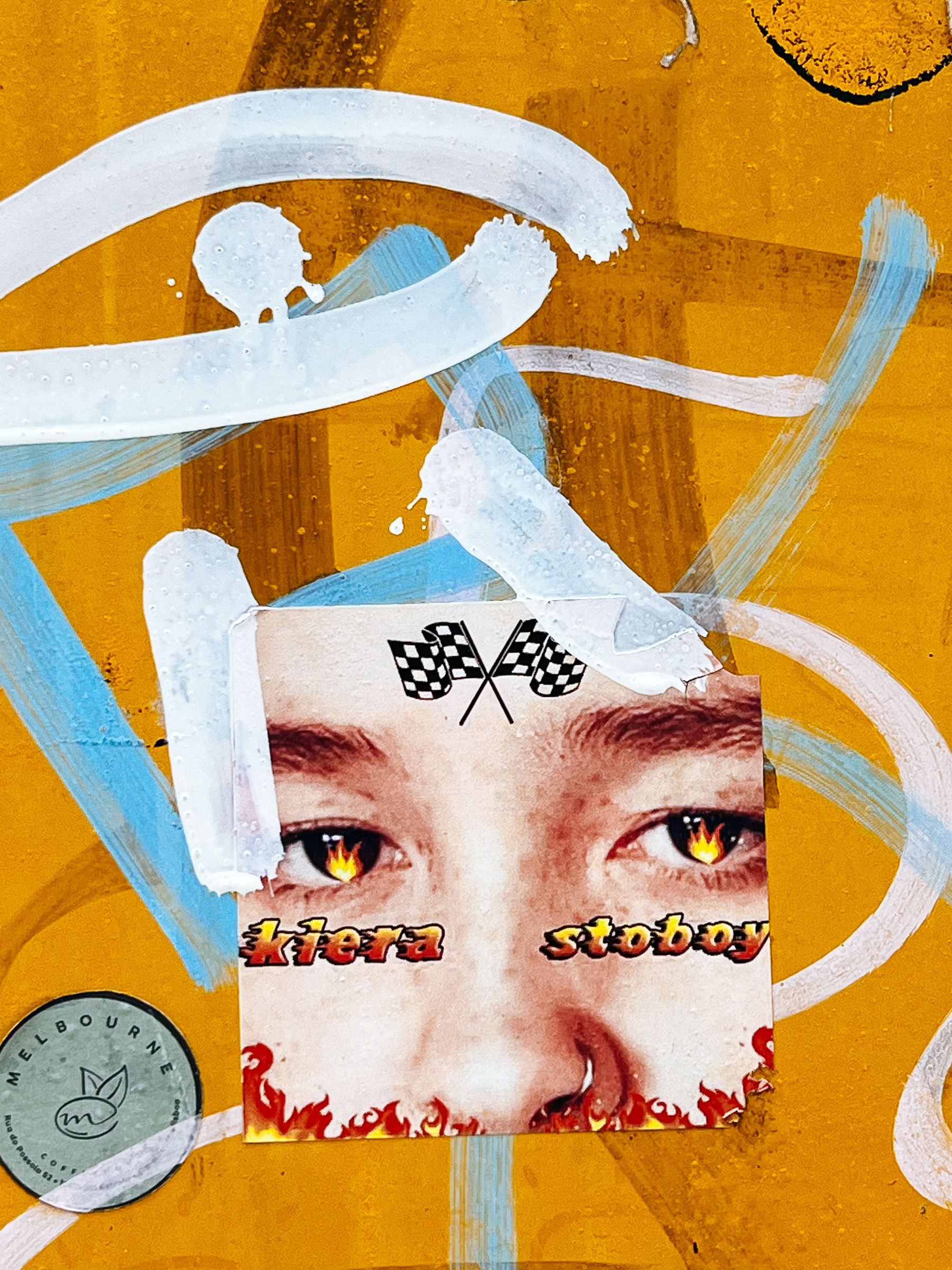 A square sticker, a close up of eyes and nose photo. The eyes have fire in them. There&rsquo;s a nose ring, and some flames under the nose. Checkered flags on the forehead. The words &ldquo;Kiera Stoboy&rdquo; under the eyes.