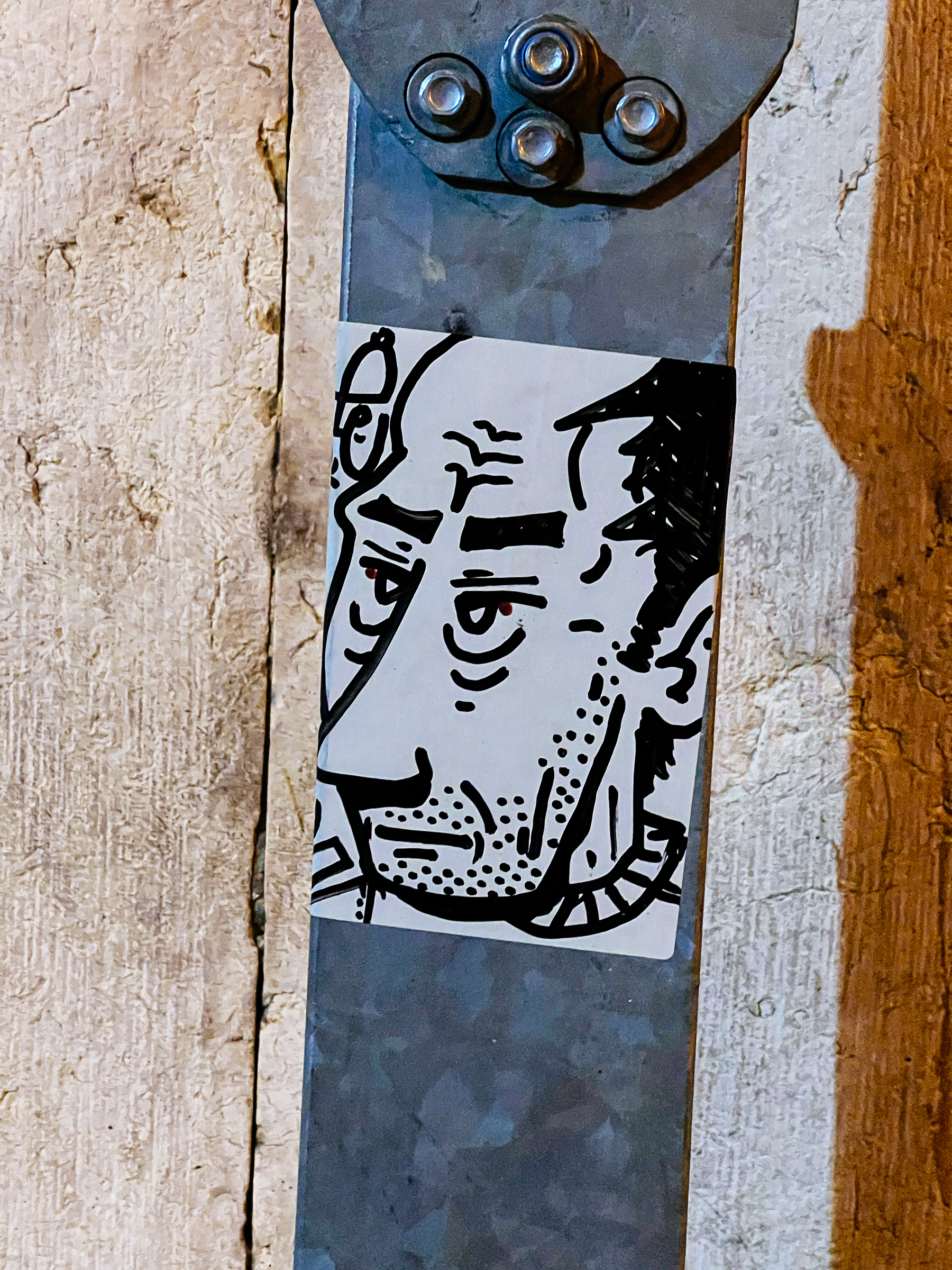 Drawing of an unshaven, tired looking, man. In a sticker. 